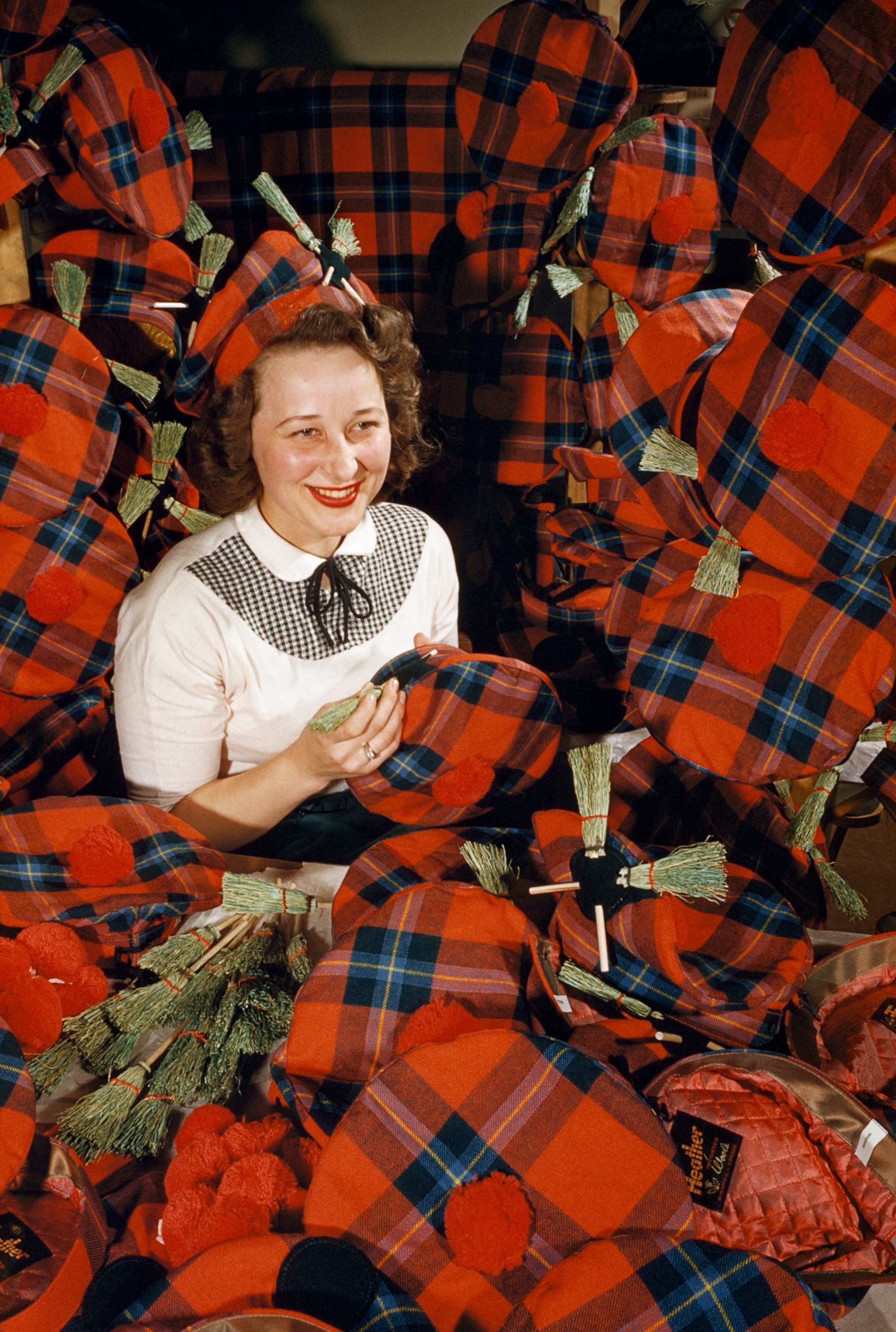 Woman decorates tartan tams with cockades of small curling brooms.