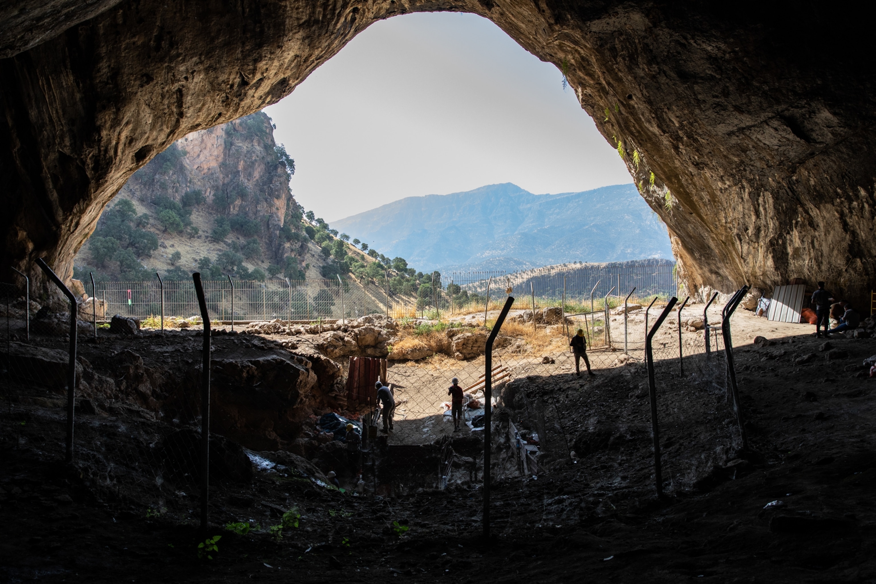 A view looking out from a cave, where a team of archeologists are working.