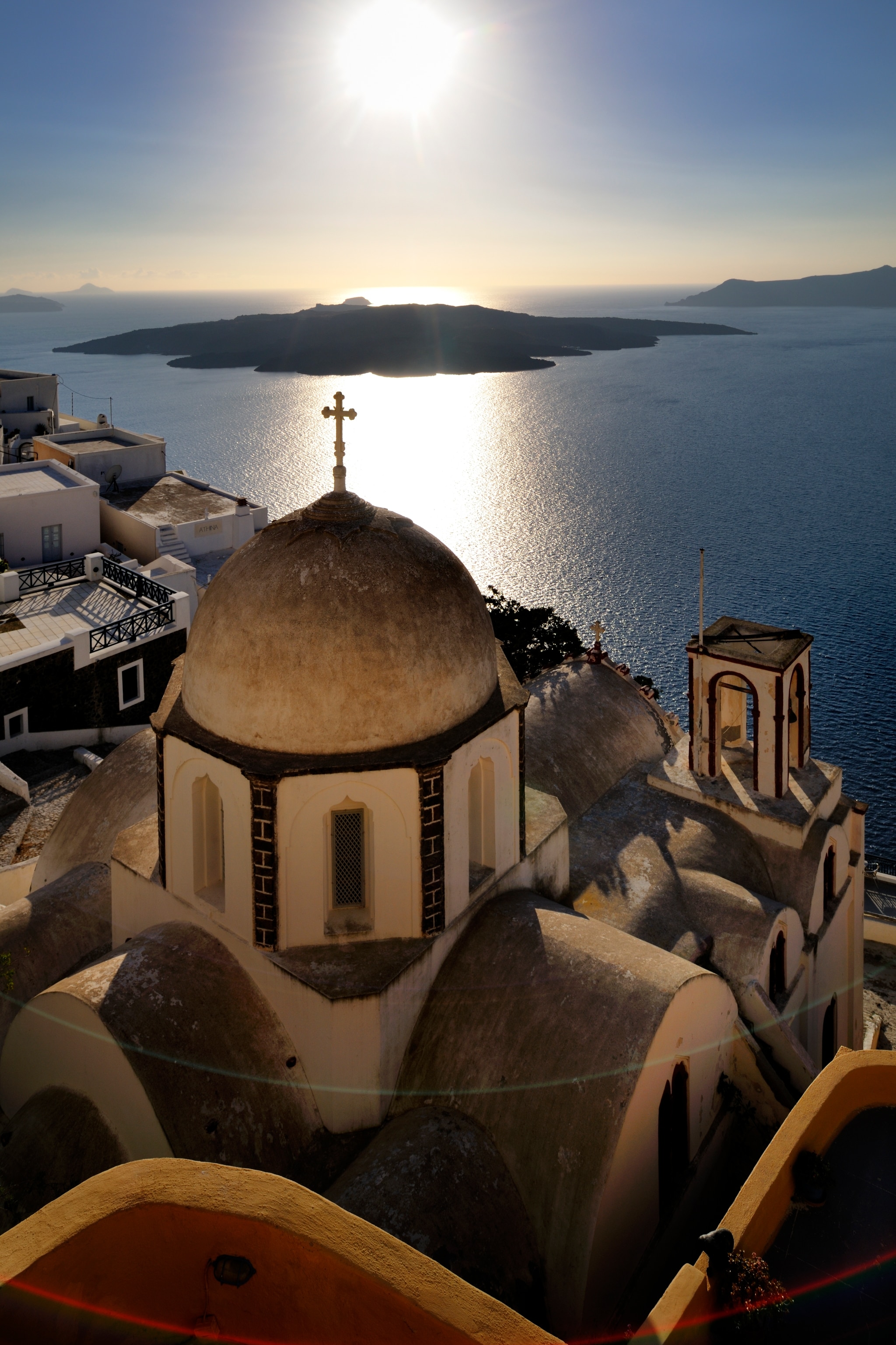 A church overlooks an island over a bright sun.