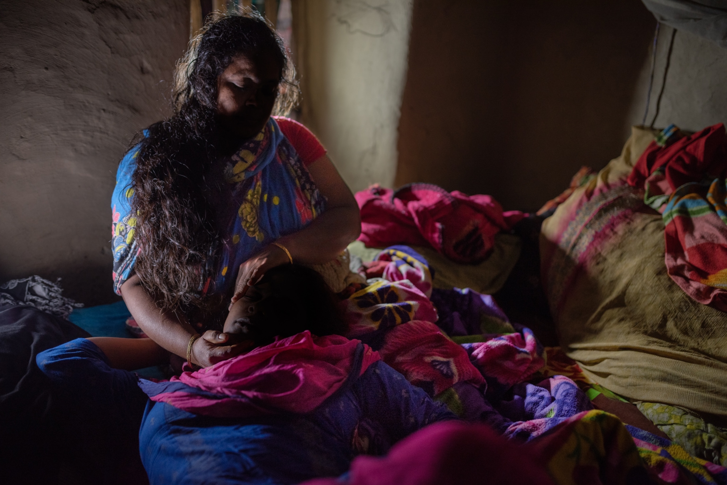 a woman lies in with her head on her mothers lap on a bed