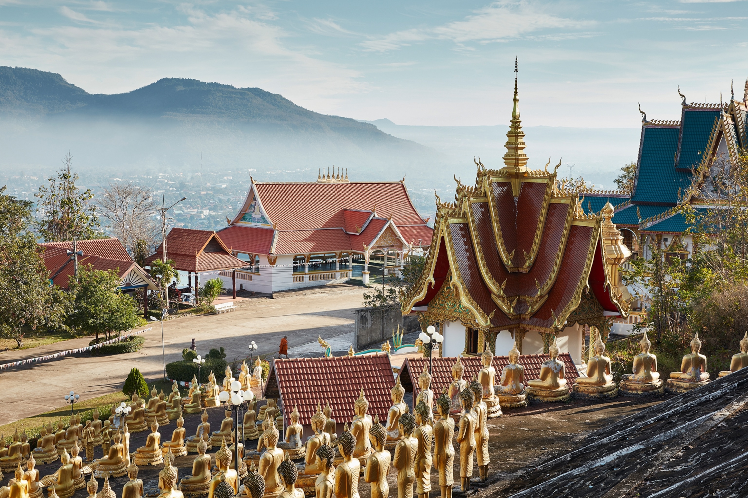 Buddhist temple on a hill, lined with golden Buddha statues.
