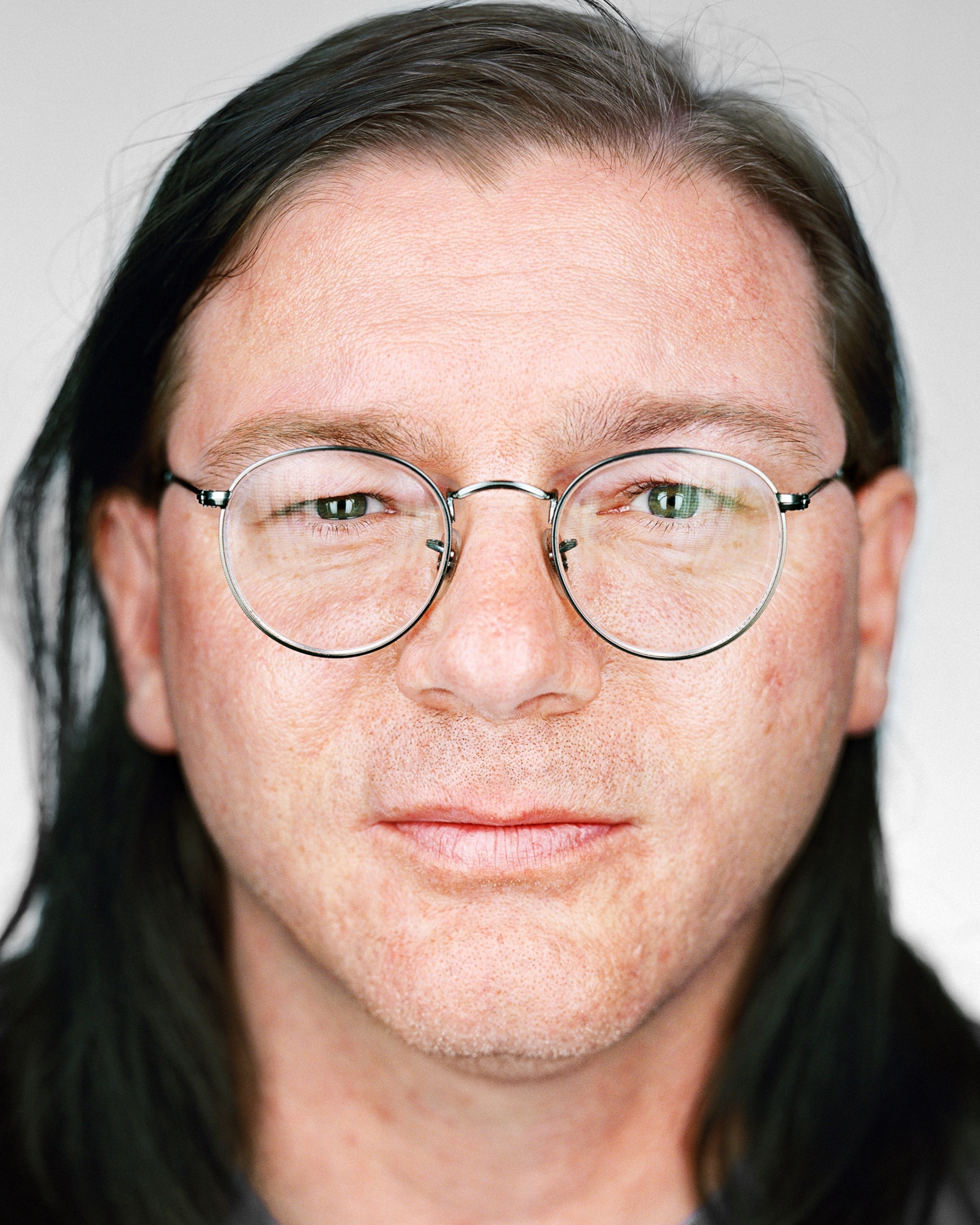 man in round eyeglasses with long dark hair