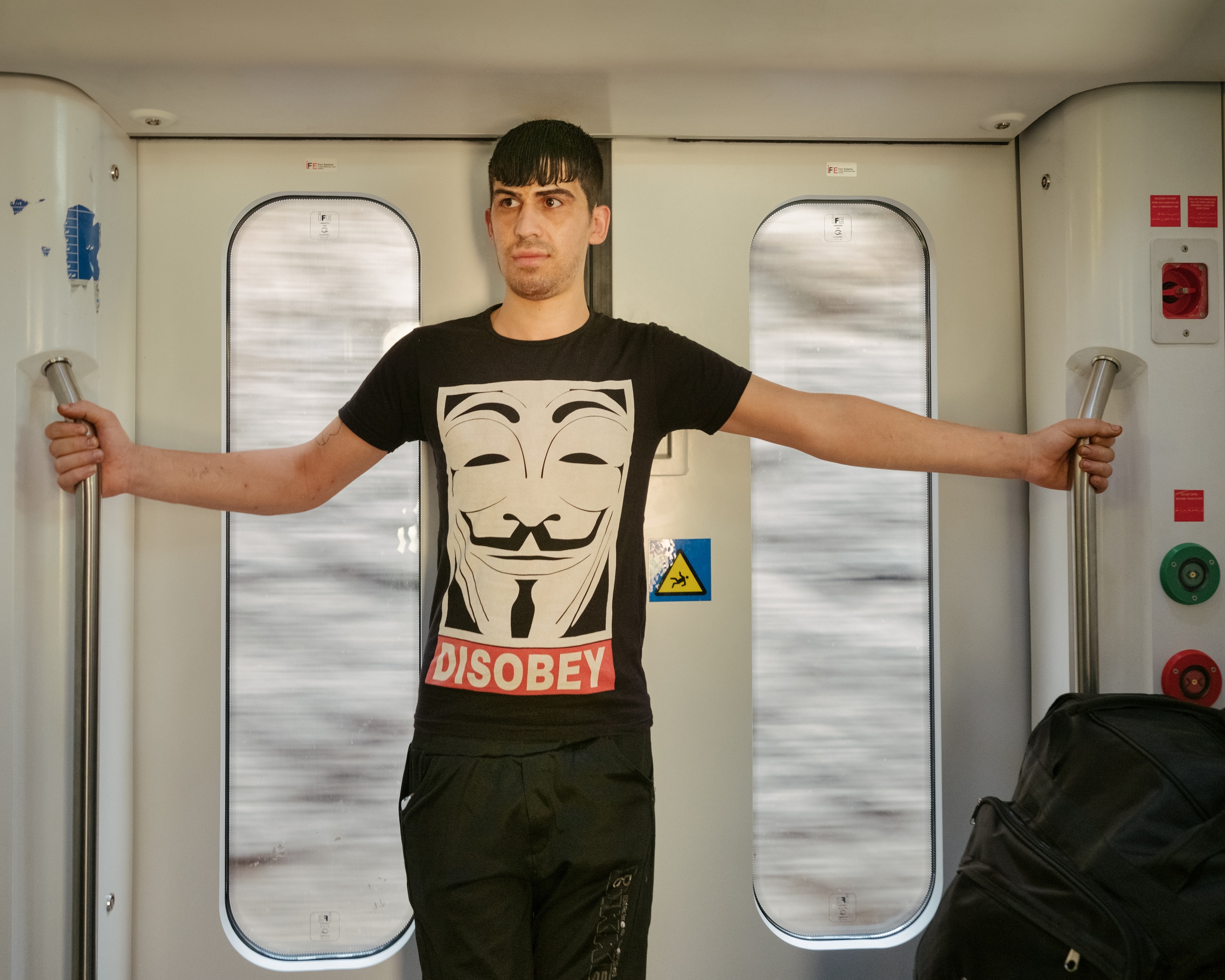 A person leans on the door as a train travels through the Zagros mountains