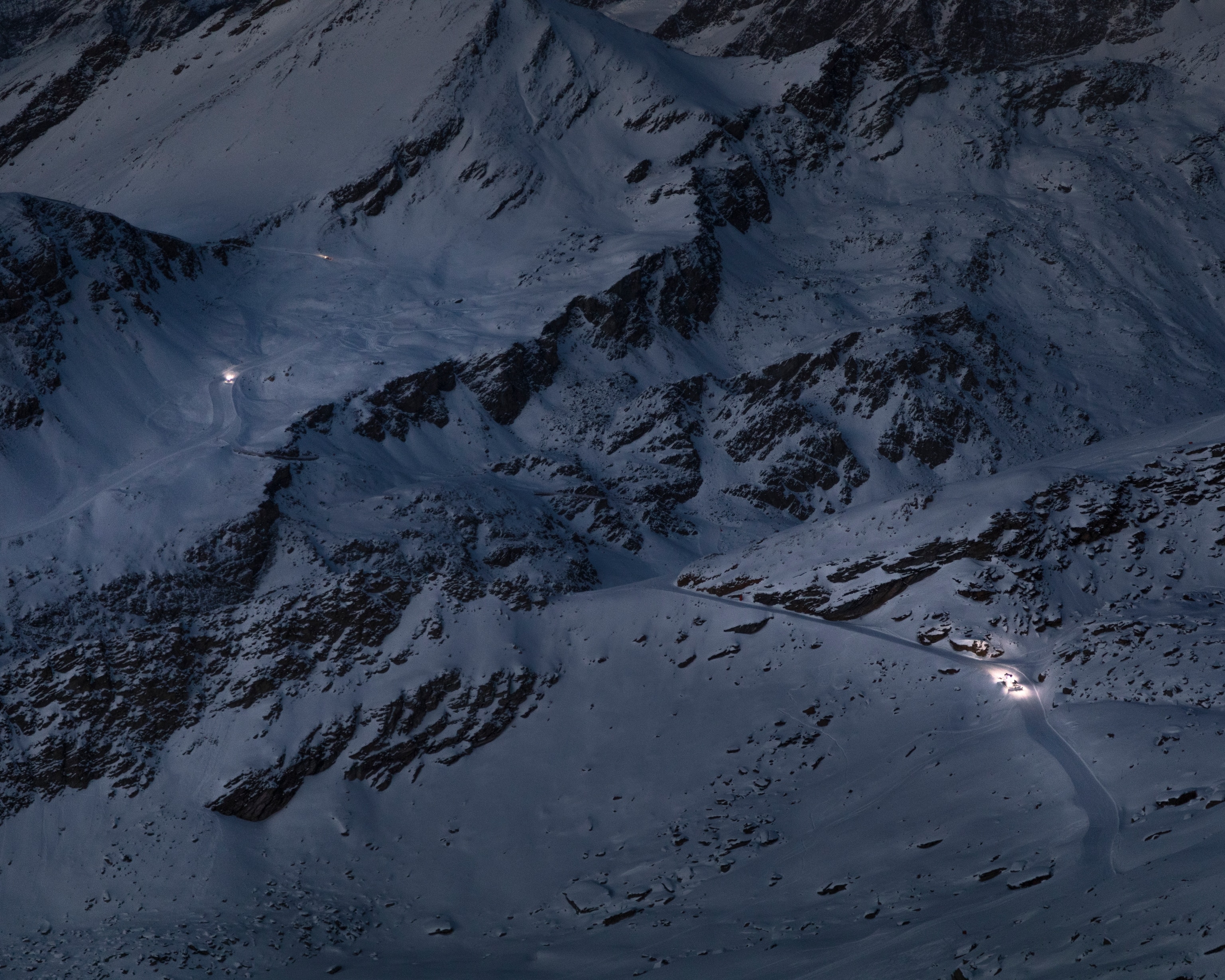 the mountain dark, illuminated by two snowcats