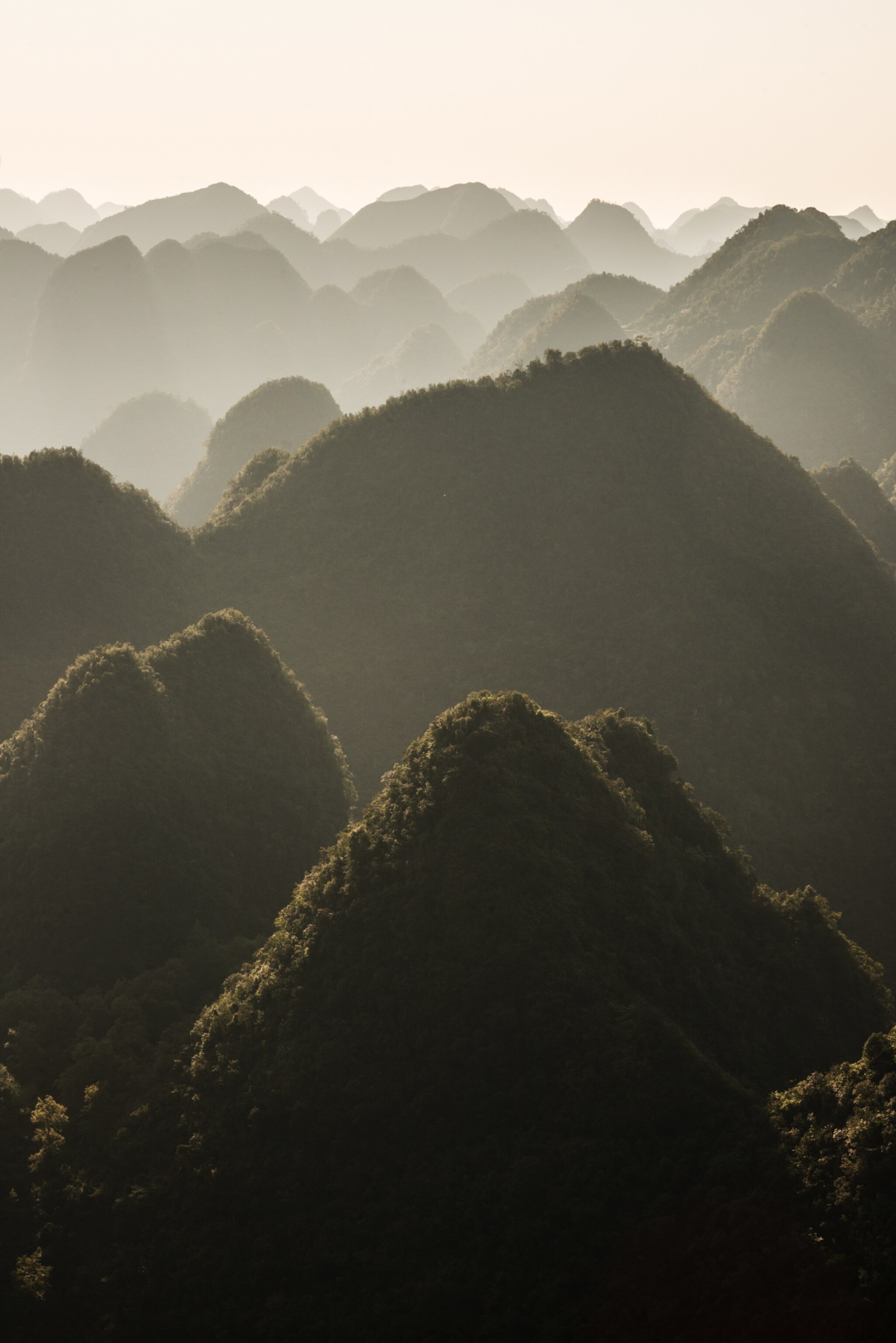 An aerial view of seemingly endless mounds of tree-covered karst mountain tops.