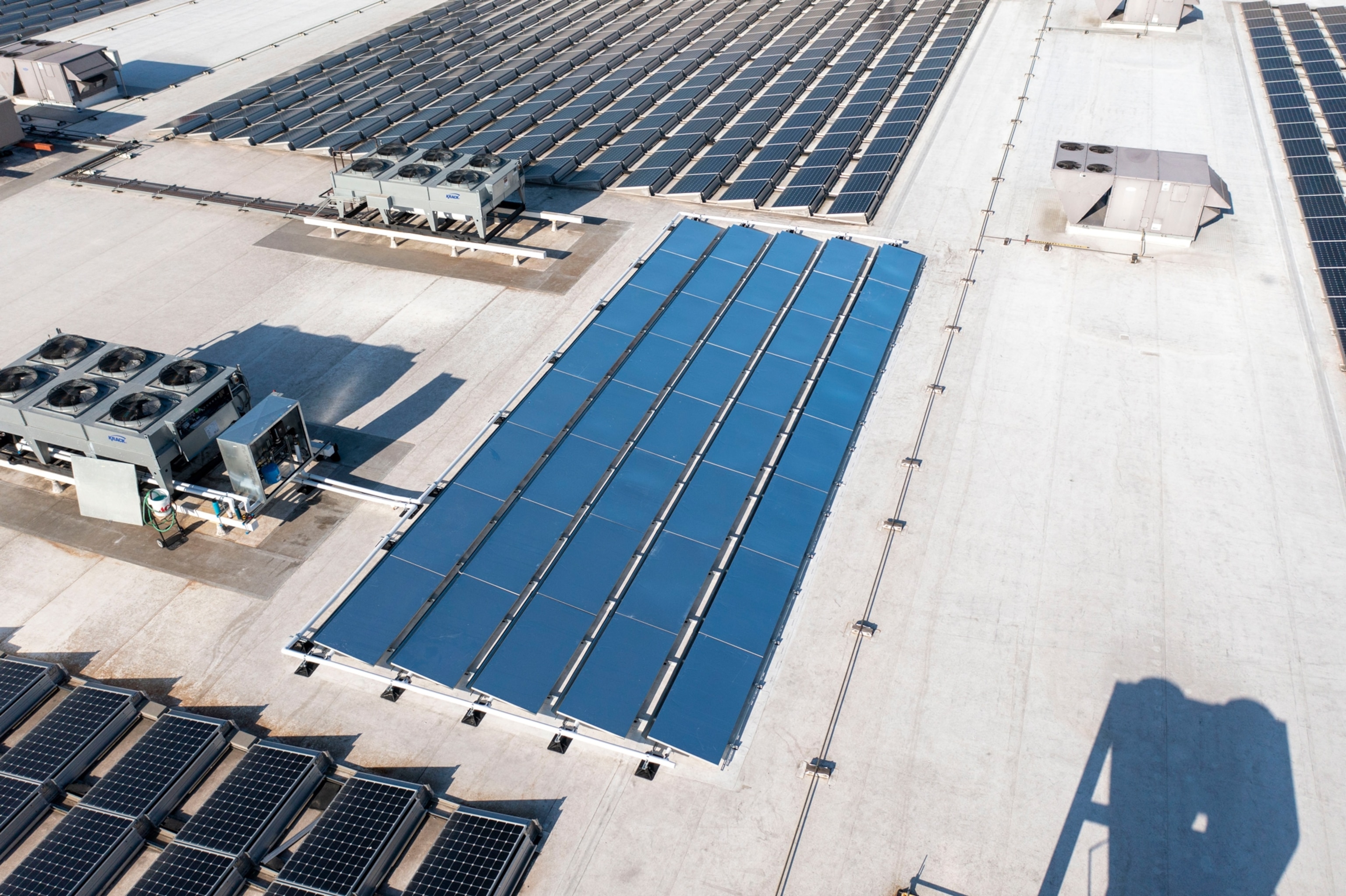 a grid of reflective grey panels on a rooftop with solar panels nearby