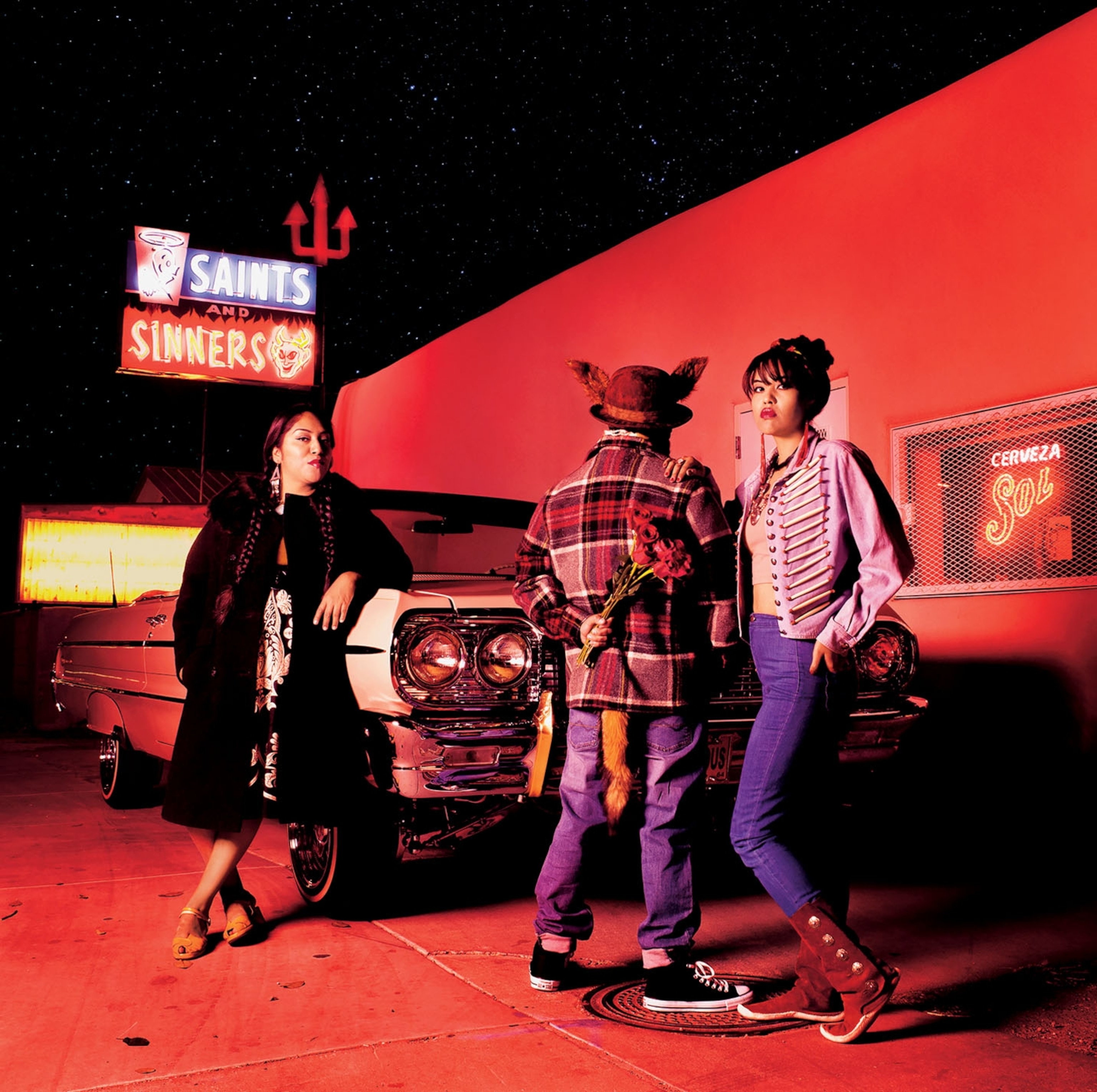 three young people posing for a portrait at night by a car