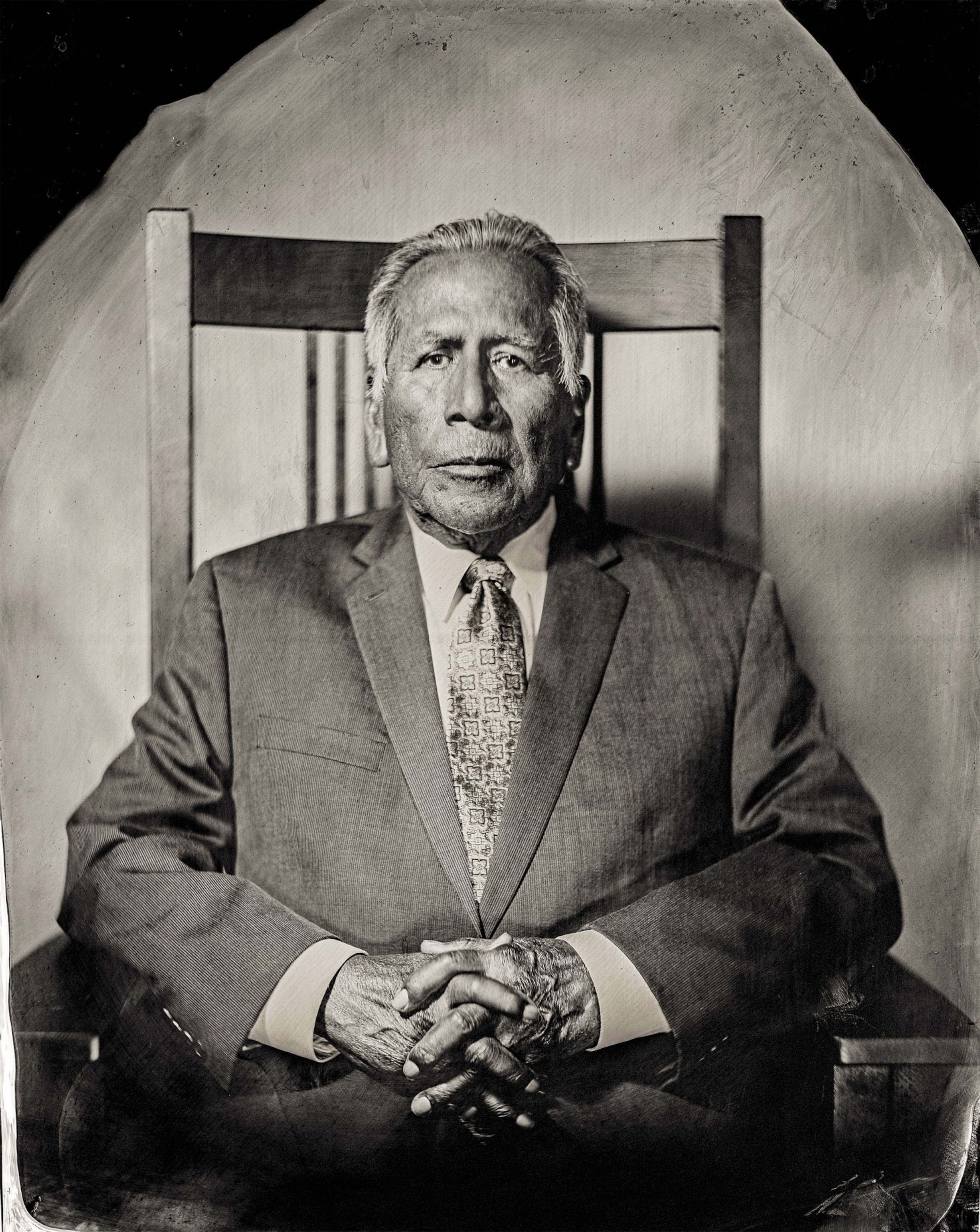 a tintype of an older man in a suite sitting in a chair