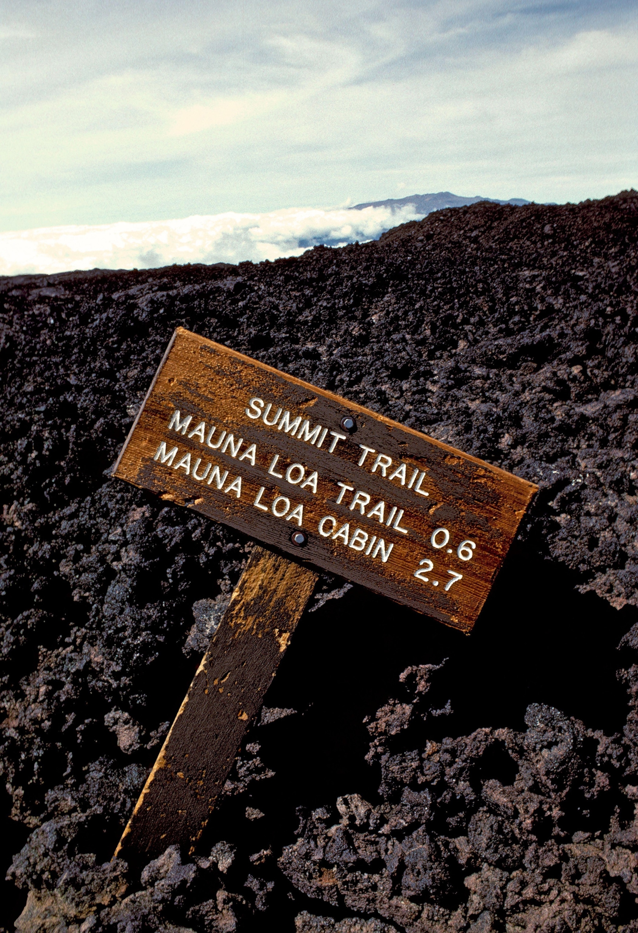 A fallen sign for Mauna Loa cabin and trail appears on the barren landscape of the mountain.