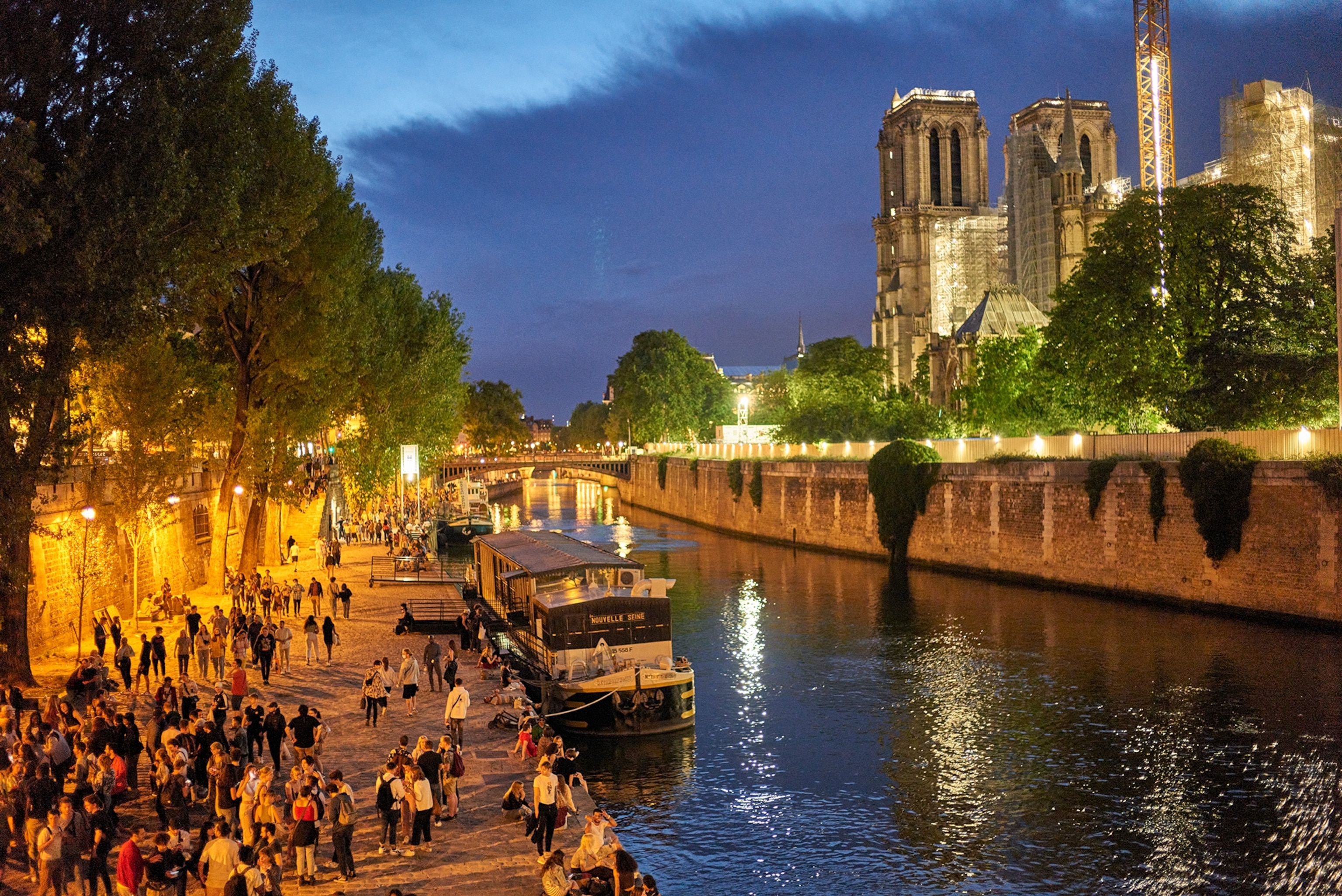 People celebrate the Fête de la Musique on the left bank of the Seine river near the Notre-Dame cathedral.