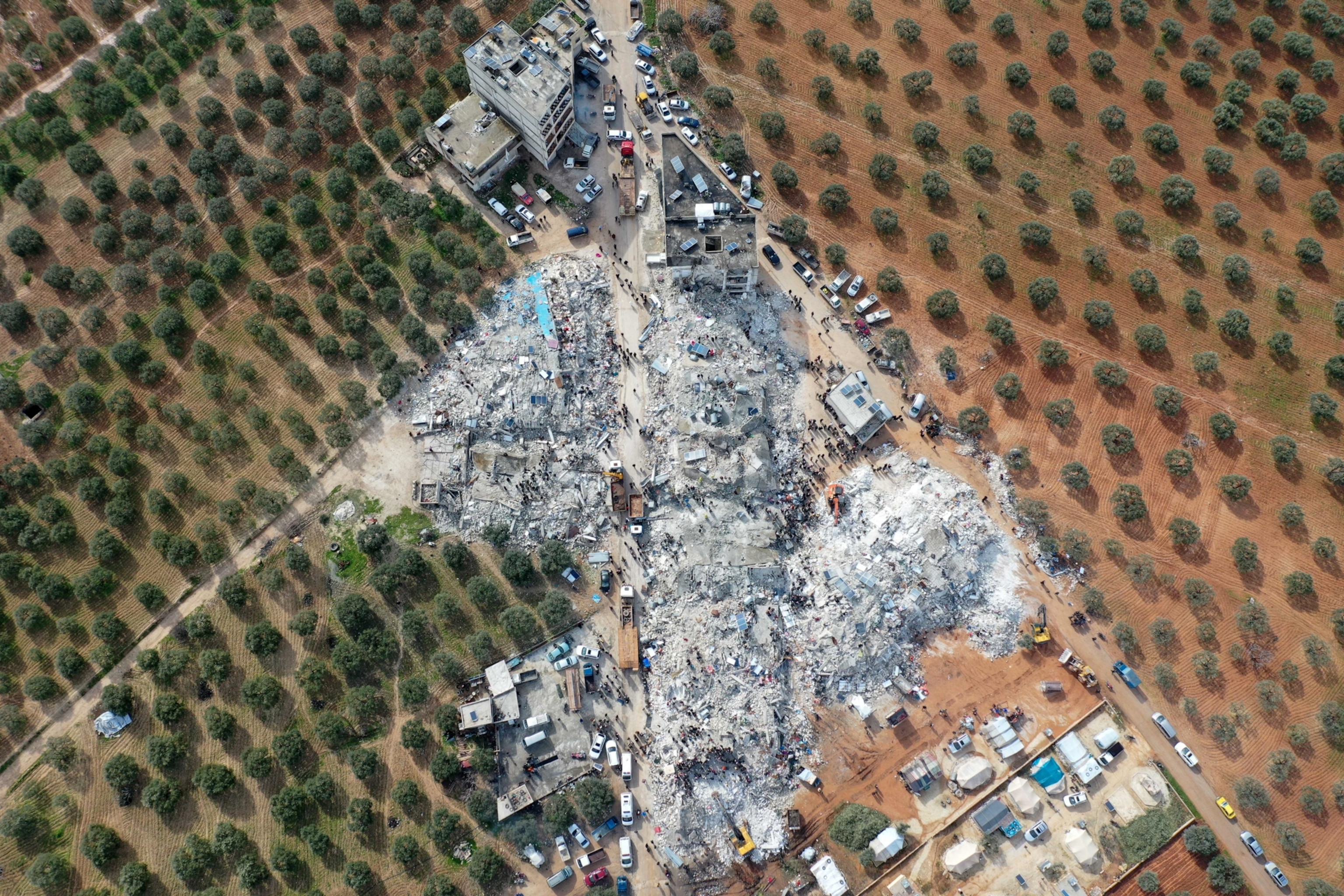 Aerial showing residents searching for victims and survivors amidst the rubble of collapsed buildings following an earthquake in the village of Besnia.
