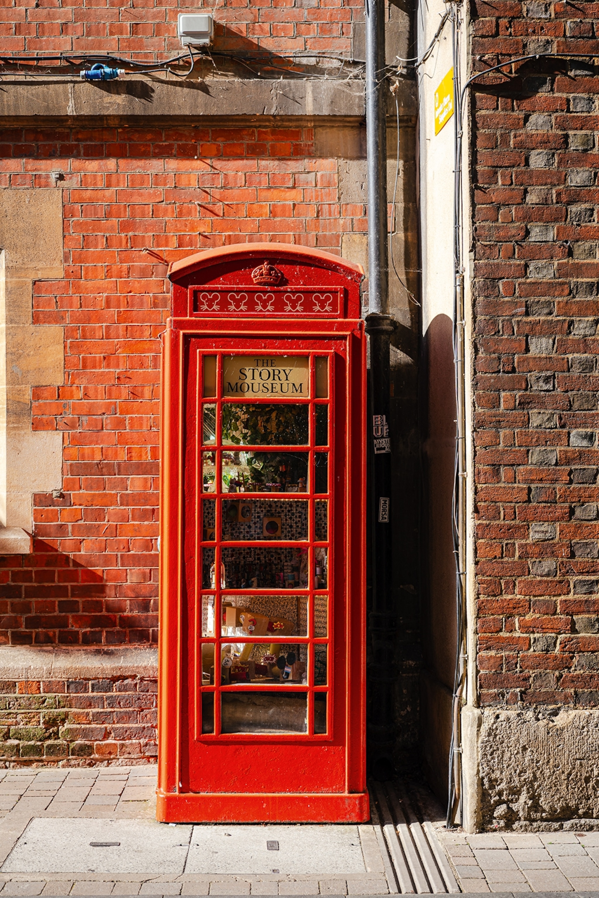 Red telephone box with a sign reading The Story Museum filled with items