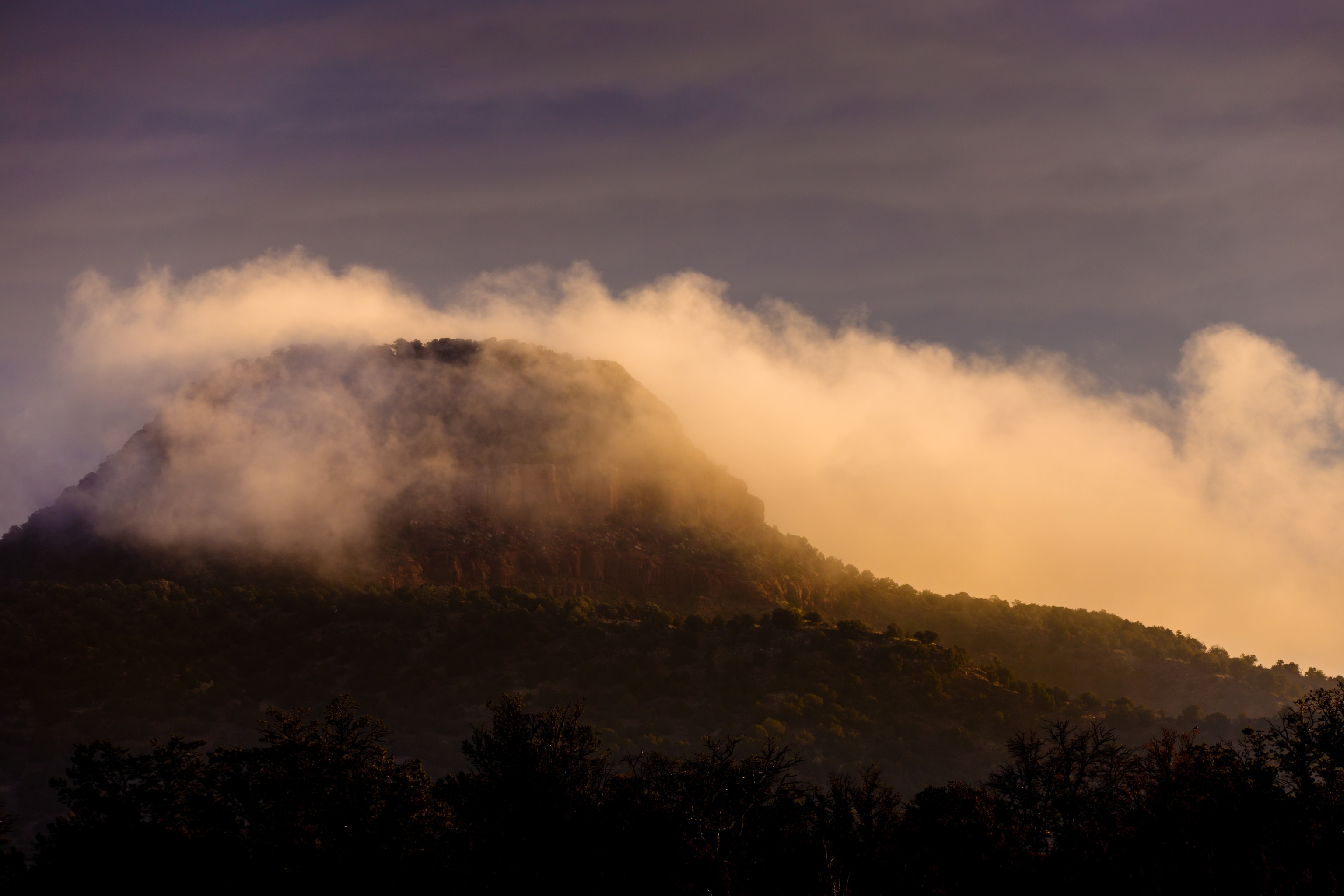 Red Butte shrouded in golden clouds during "golden hour"