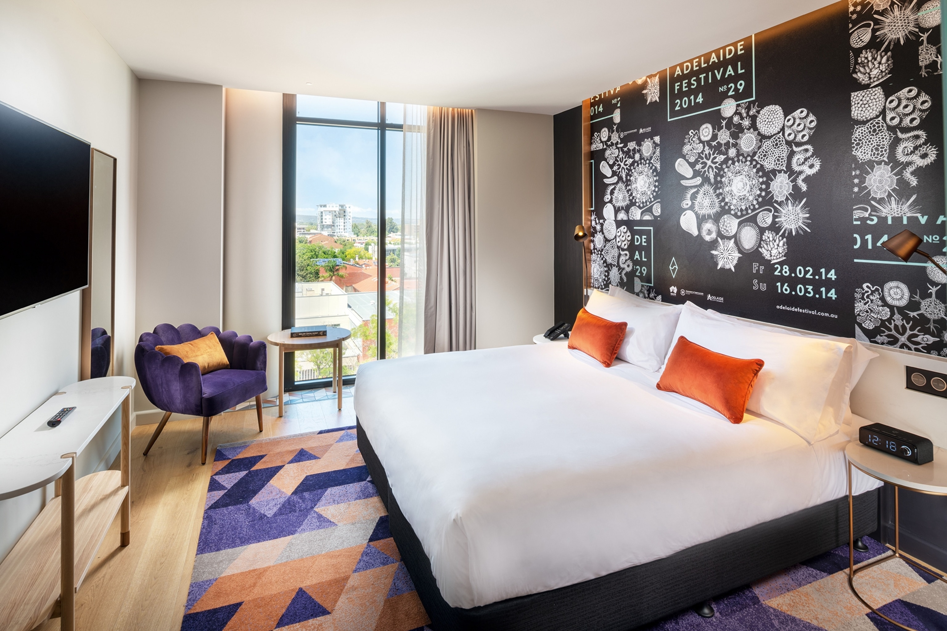 A hotel room in Adelaide. The walls are neutral and a statement wall behind the headboard is black with a white mandala pattern
