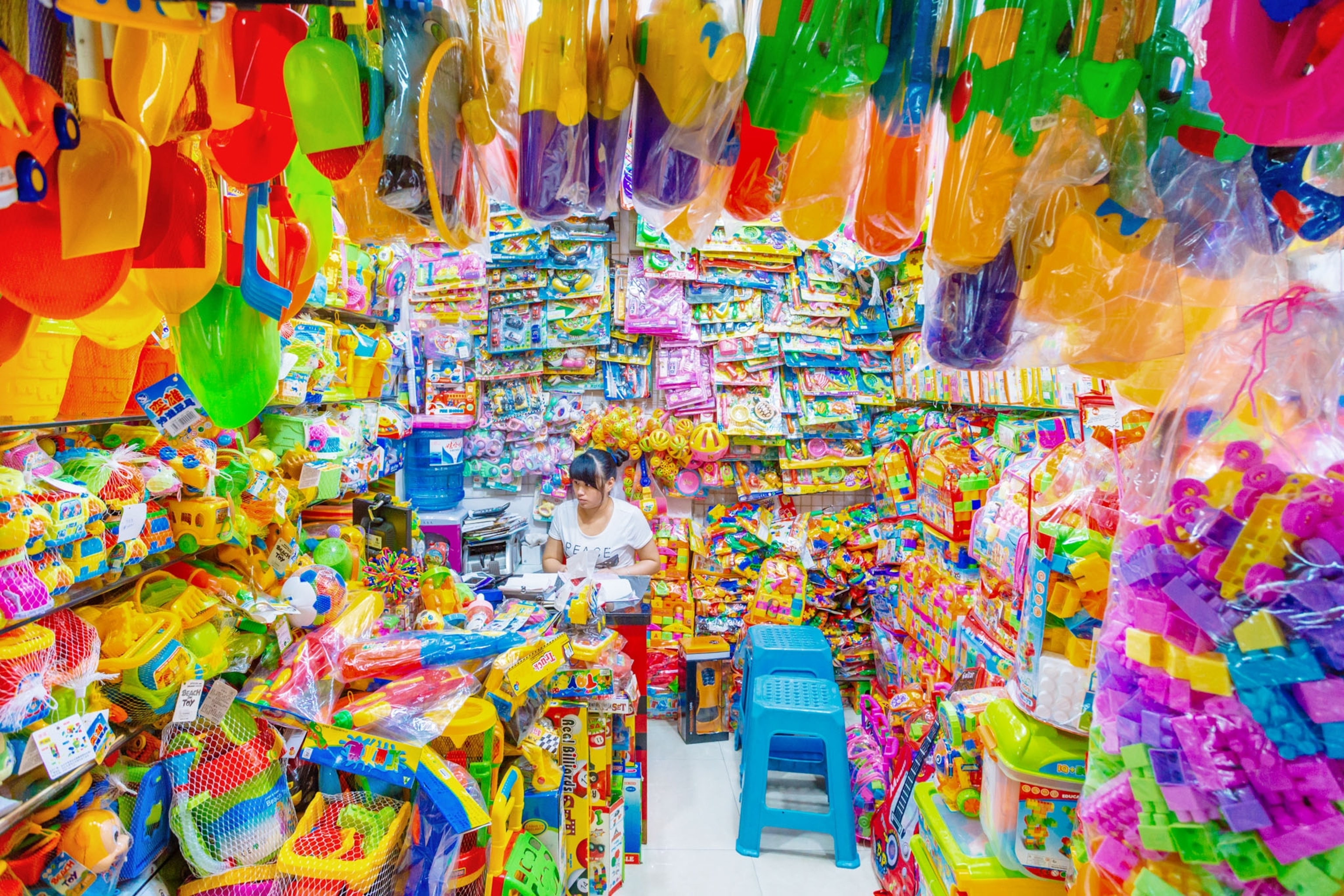 a small store filled with colorful plastic products, a woman sitting blends in