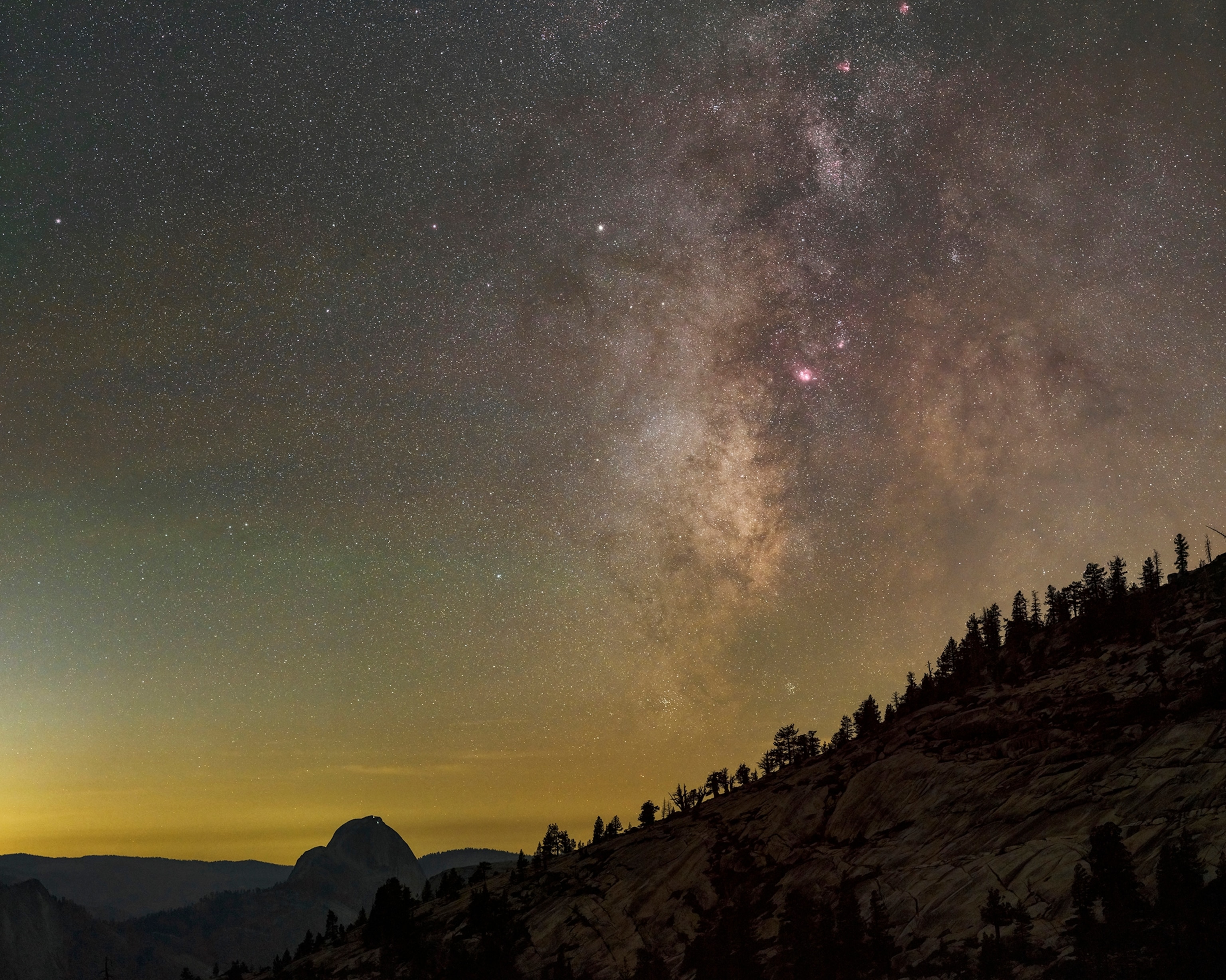 View of the Milky Way and winter stars in the night sky above Half Dome in Yosemite National Park.