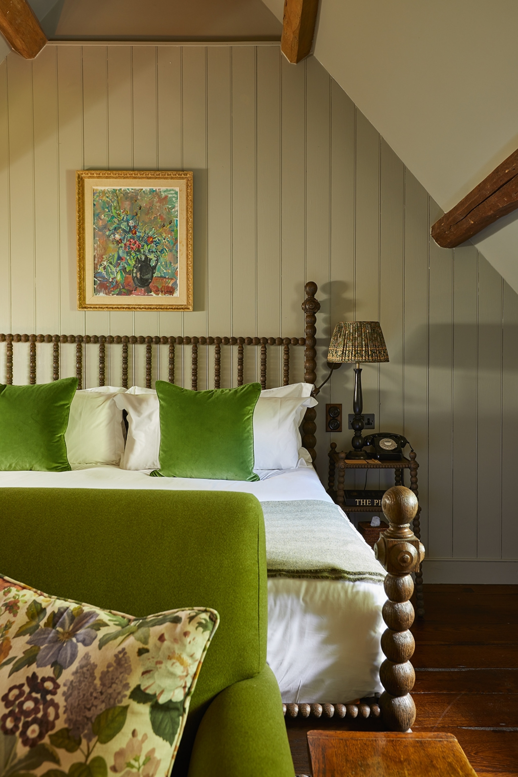 An elegant hotel bedroom with wood-panelled walls, a four-post wooden bed and floral decorations.