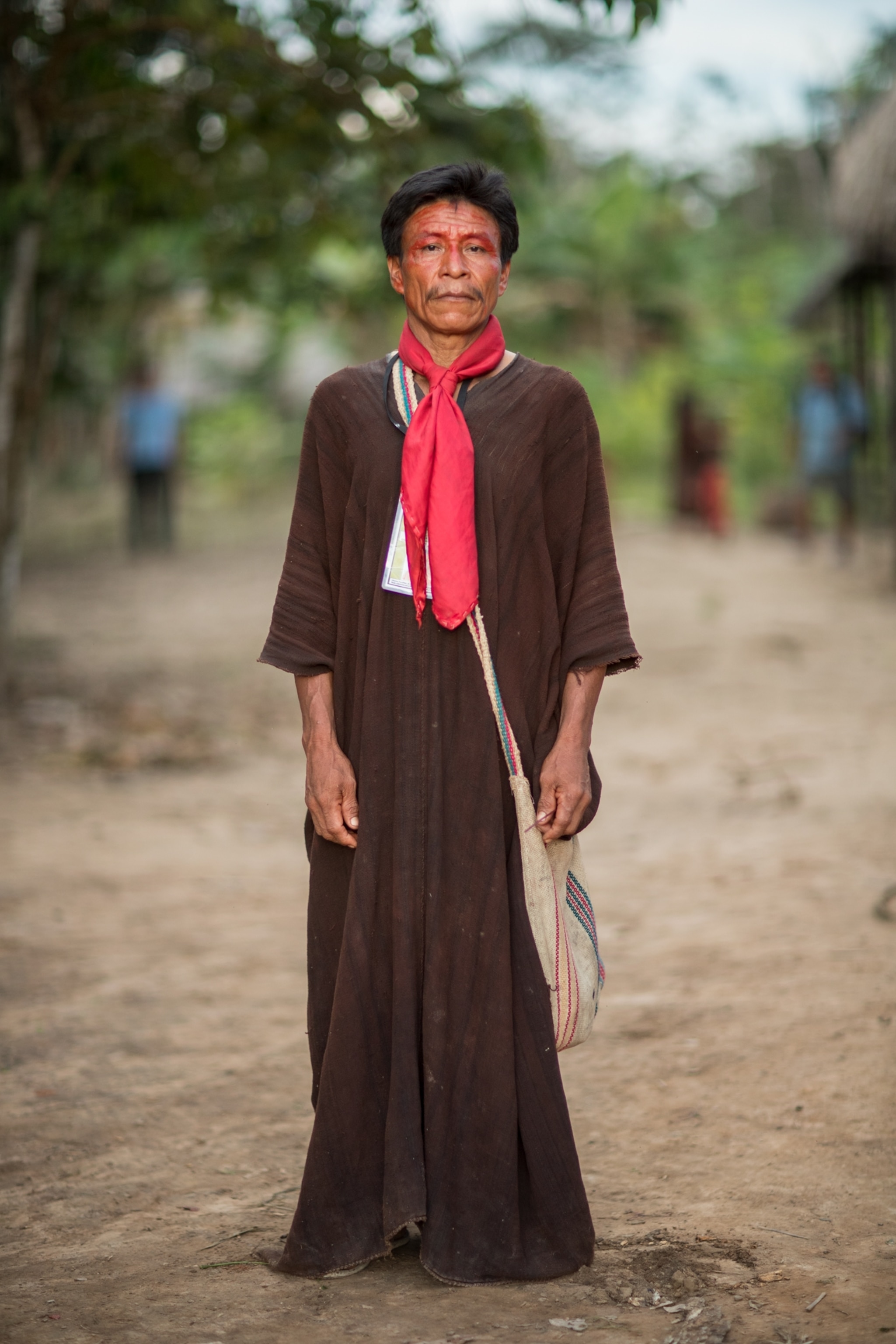 a man wearing a brown smock and a red scarf