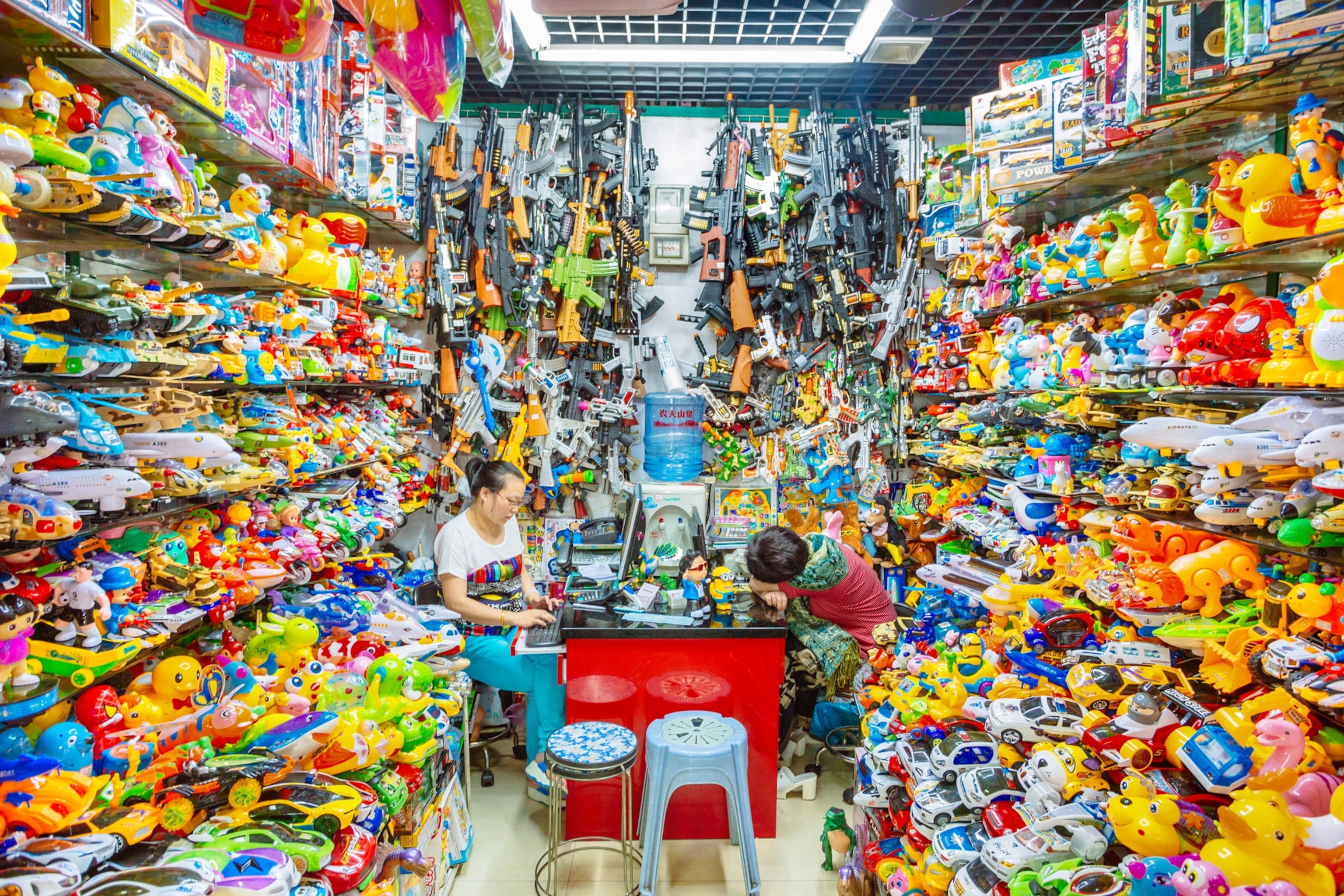 a small store filled with various plastic toys, two women sit in the center