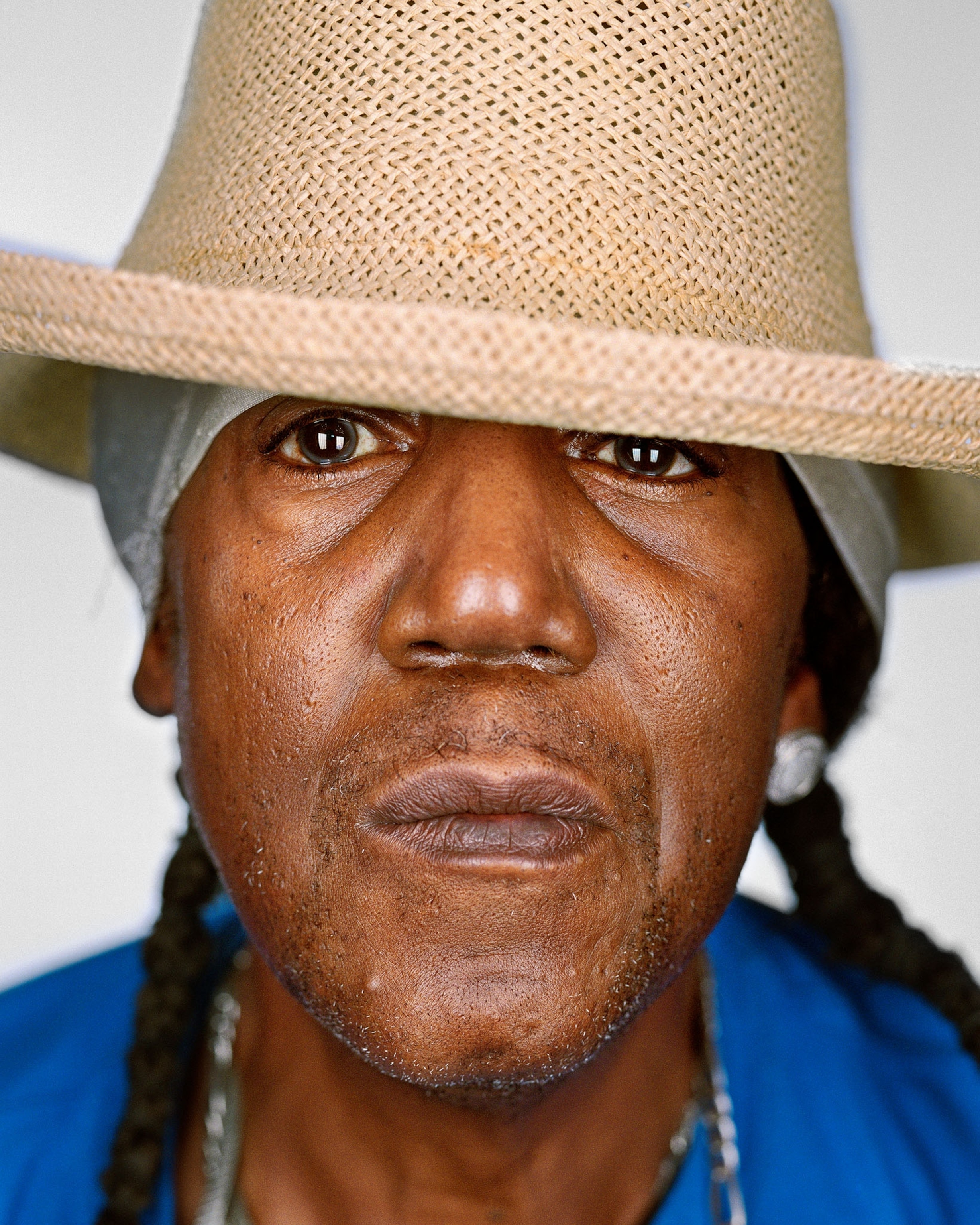 man with braided hair in straw hat.