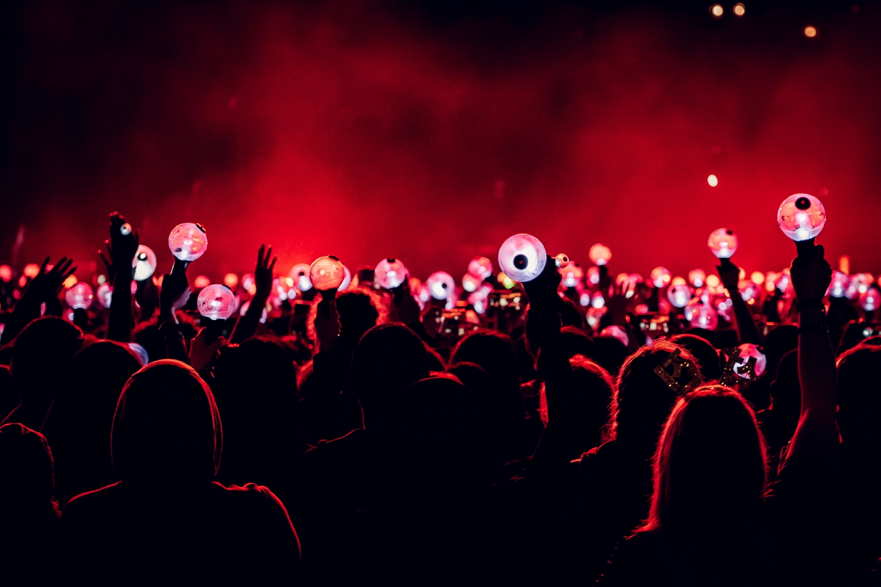 Fans hold up light globes at a concert with red lights