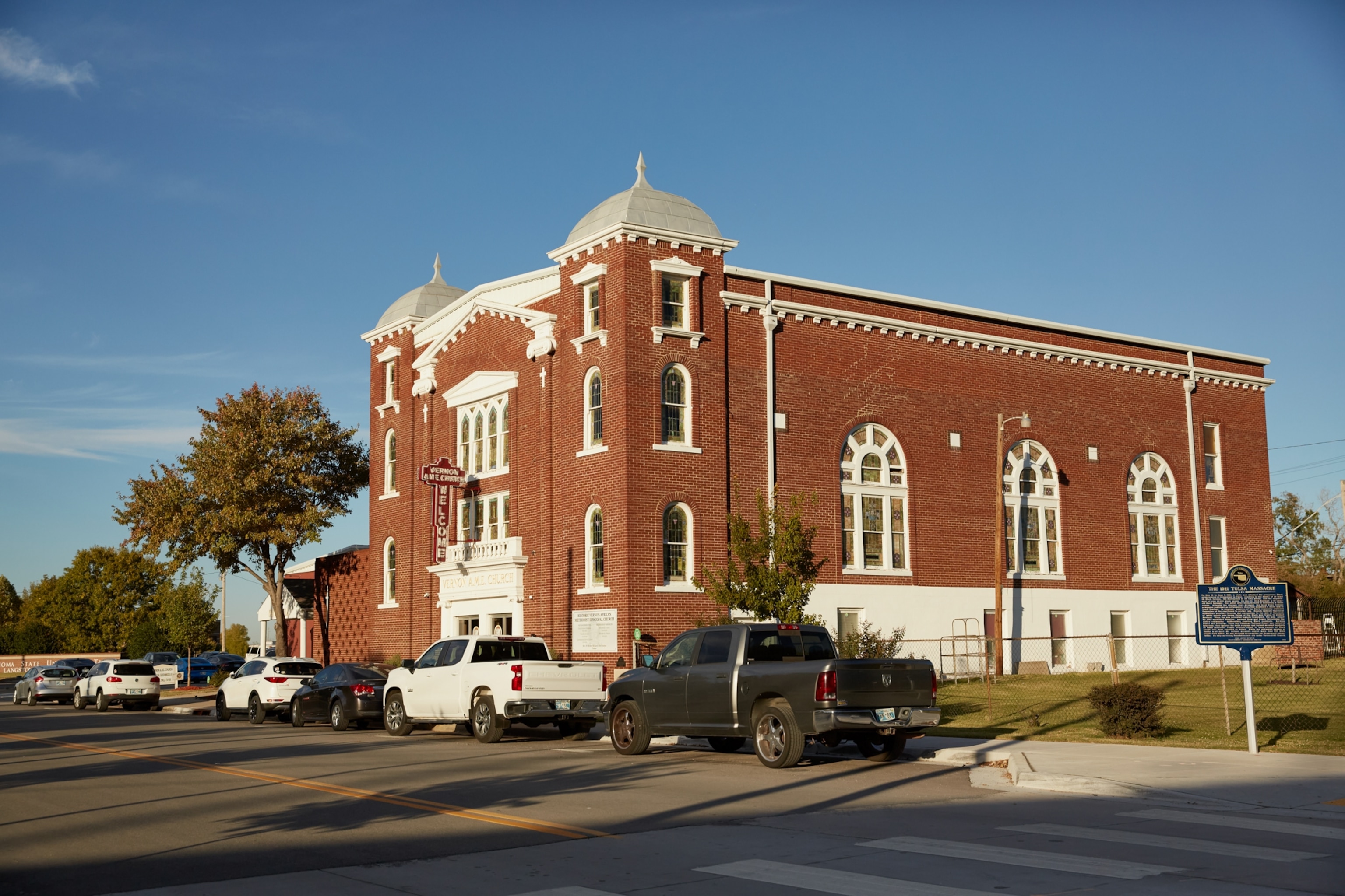 A brown brick church standing under a blue sky.