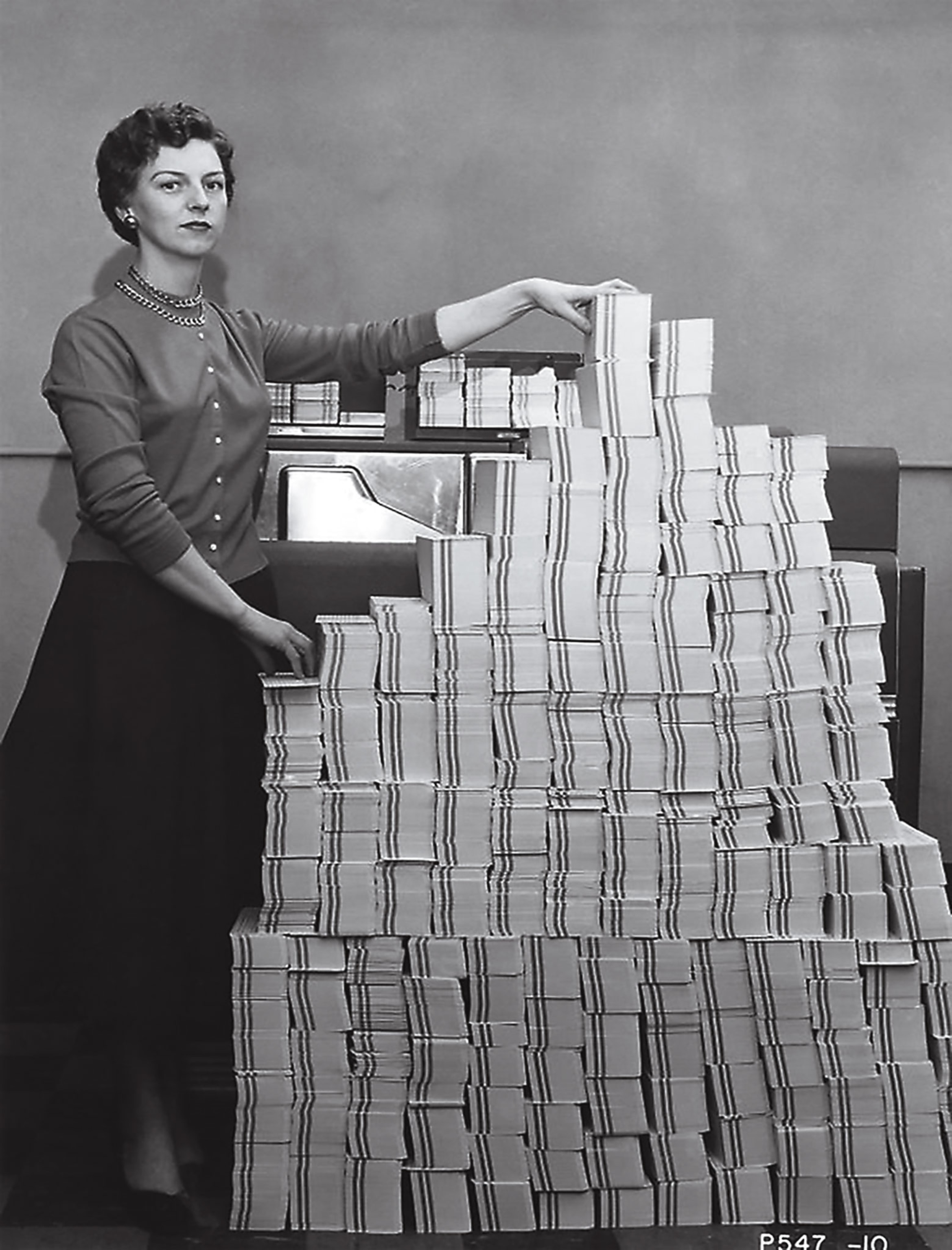 A woman stands with stacked cards in a black-and-white photo