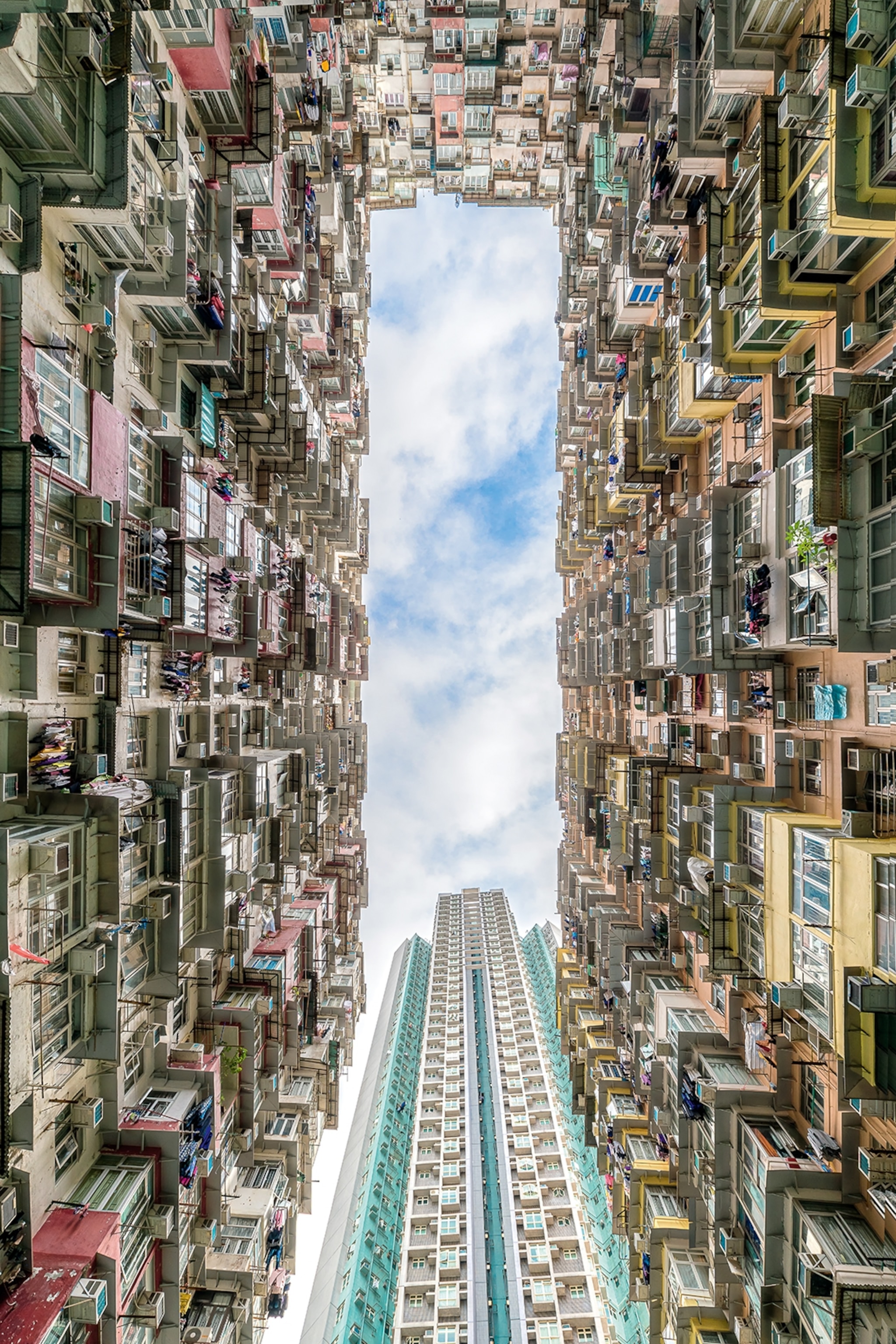 A view from the ground up into a rectangular and densely populated house courtyard with a skyscraper in the centre.