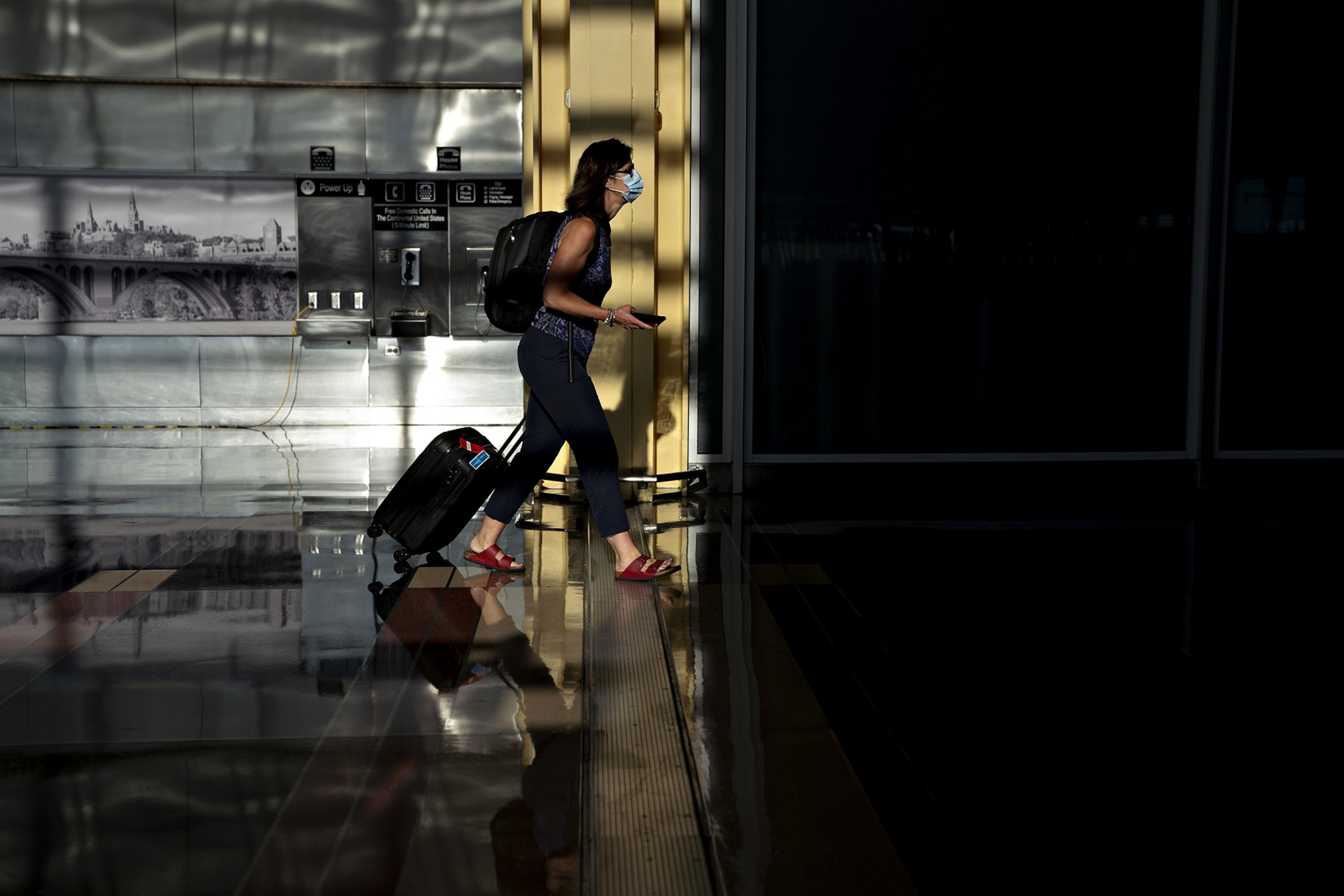 a raveler wearing a protective mask walks through Ronald Reagan National Airport