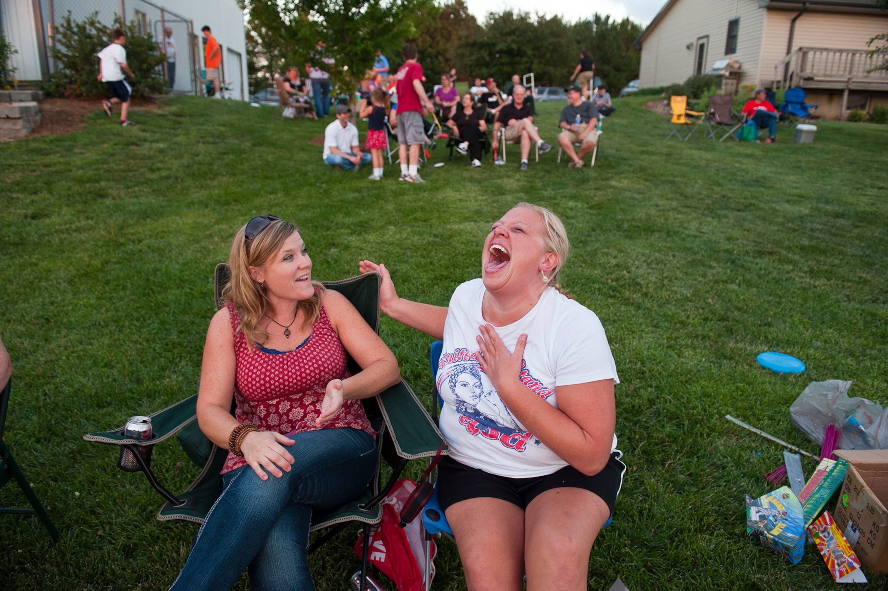 A woman laughs as she holds her chest and another smiles.