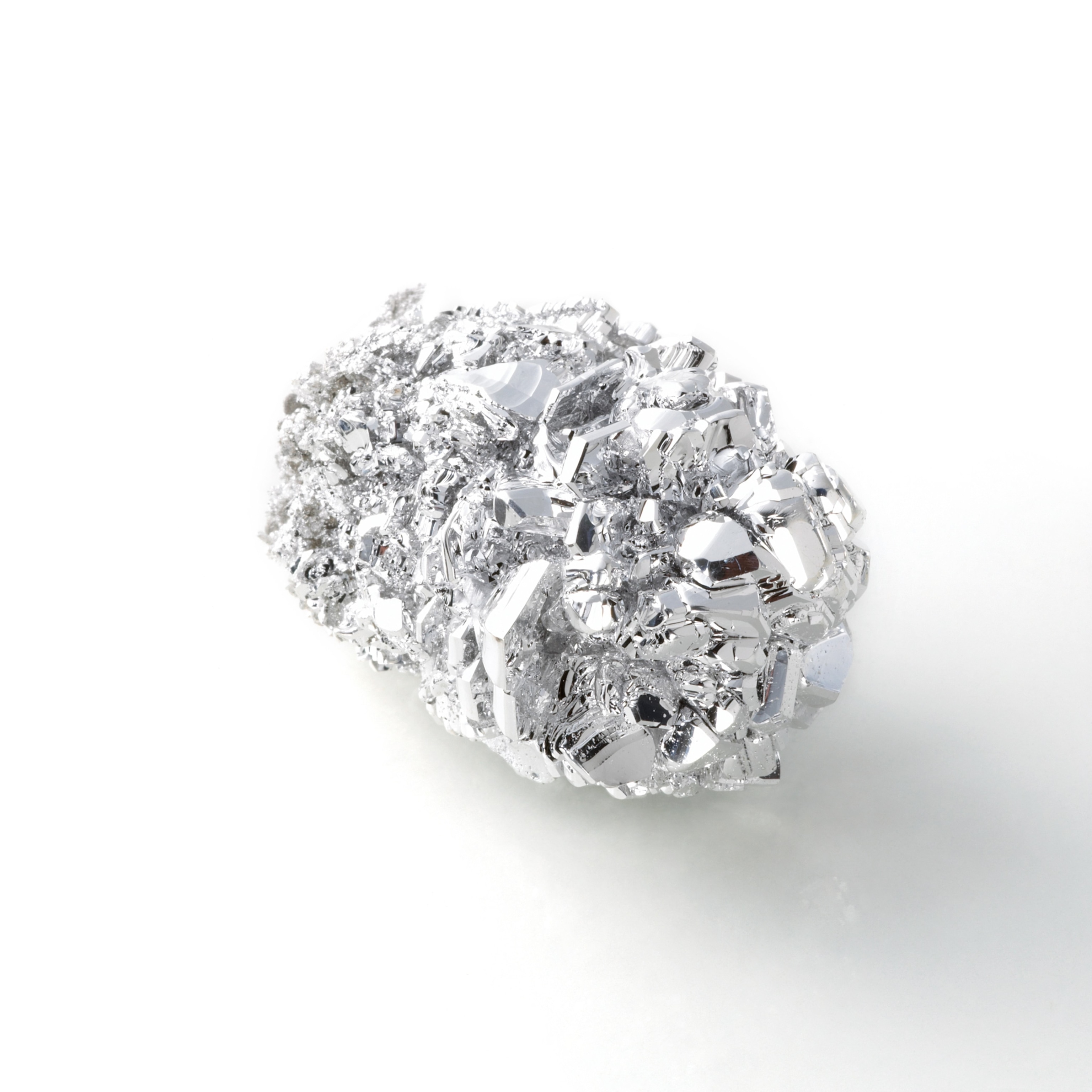 A sample of the earth metal Magnesium appears like a glossy, metal nugget.