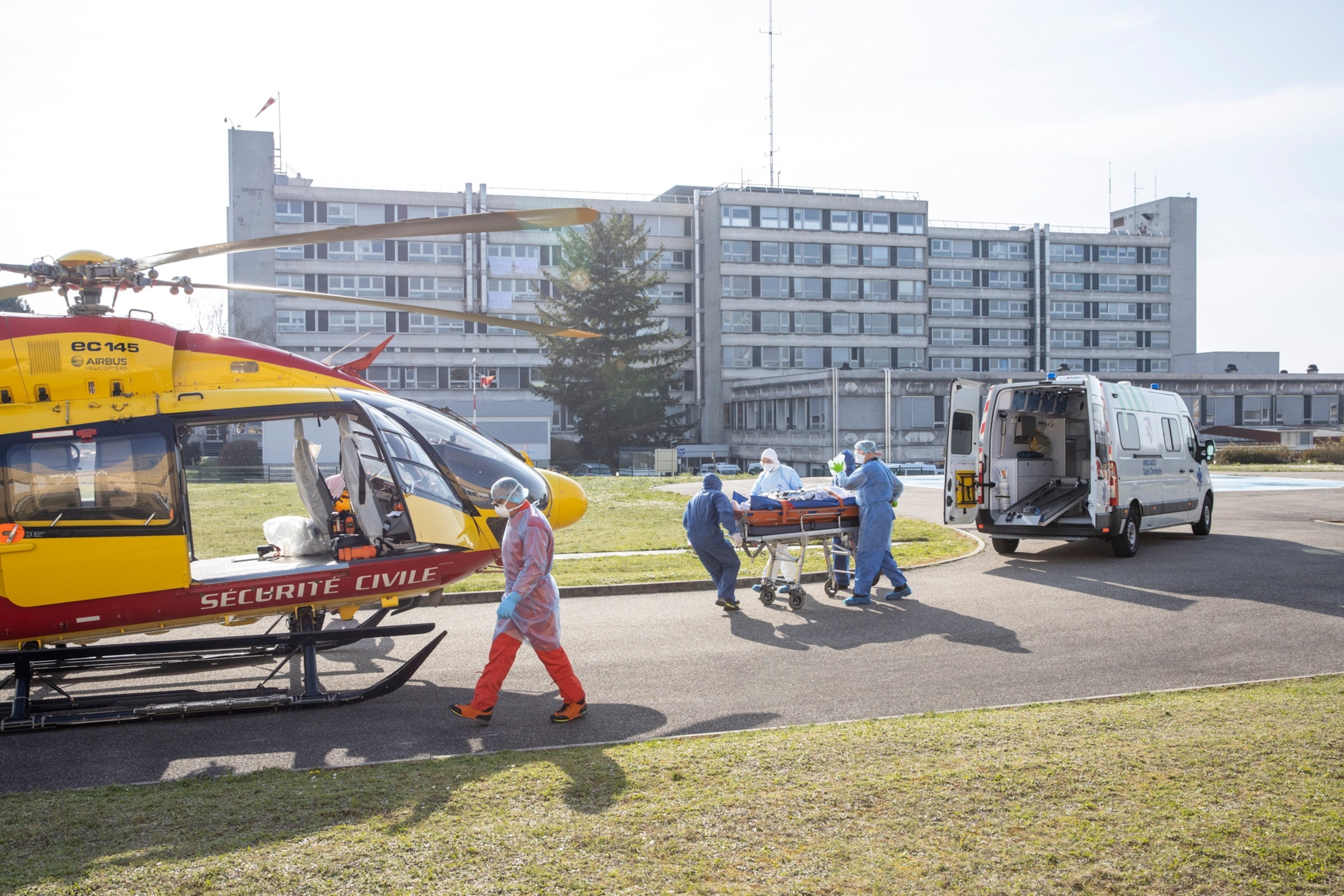 of people leading someone in gurney from an ambulance to helicopter