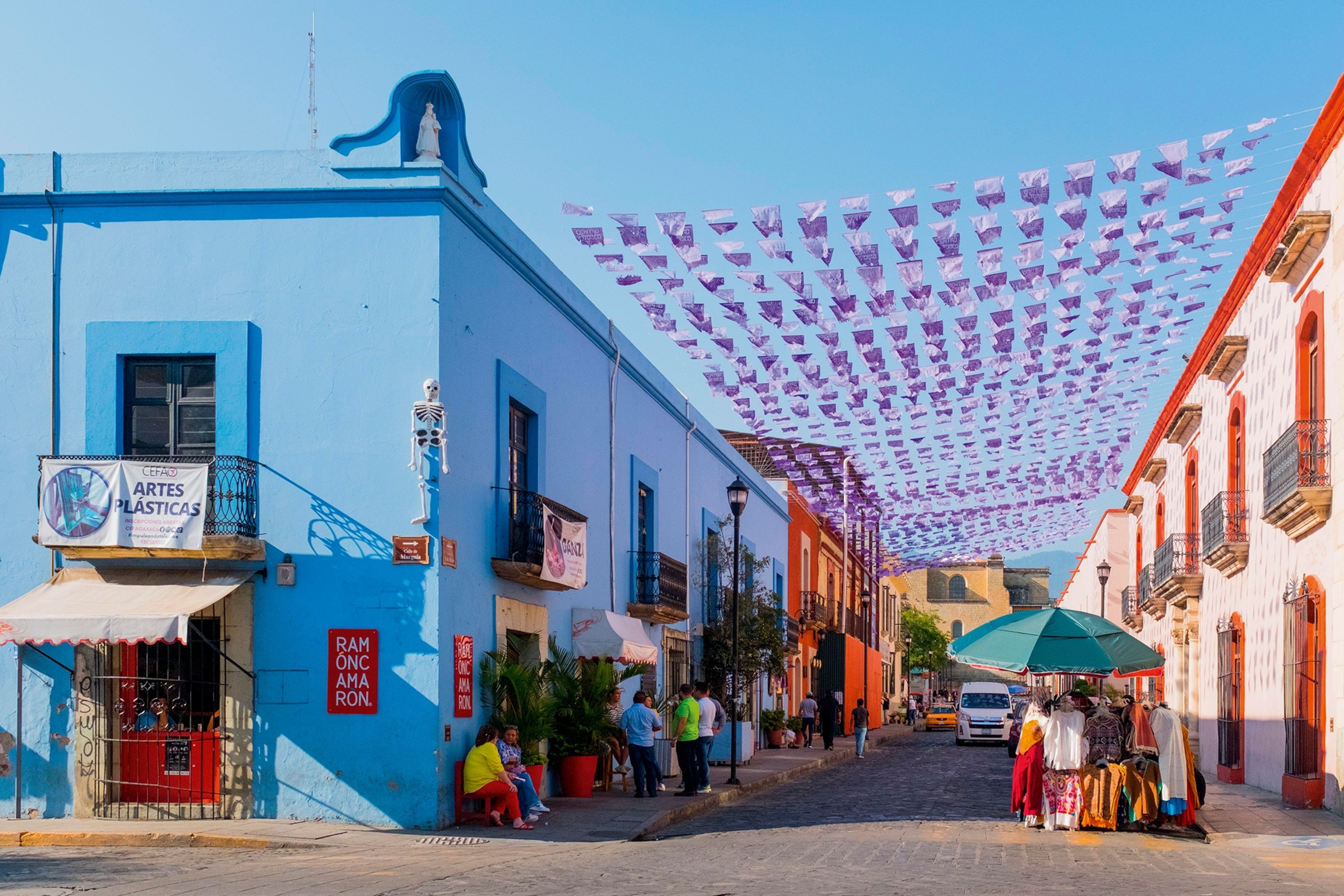 A view onto a residential street of colourful houses with garlands drawn up between them.