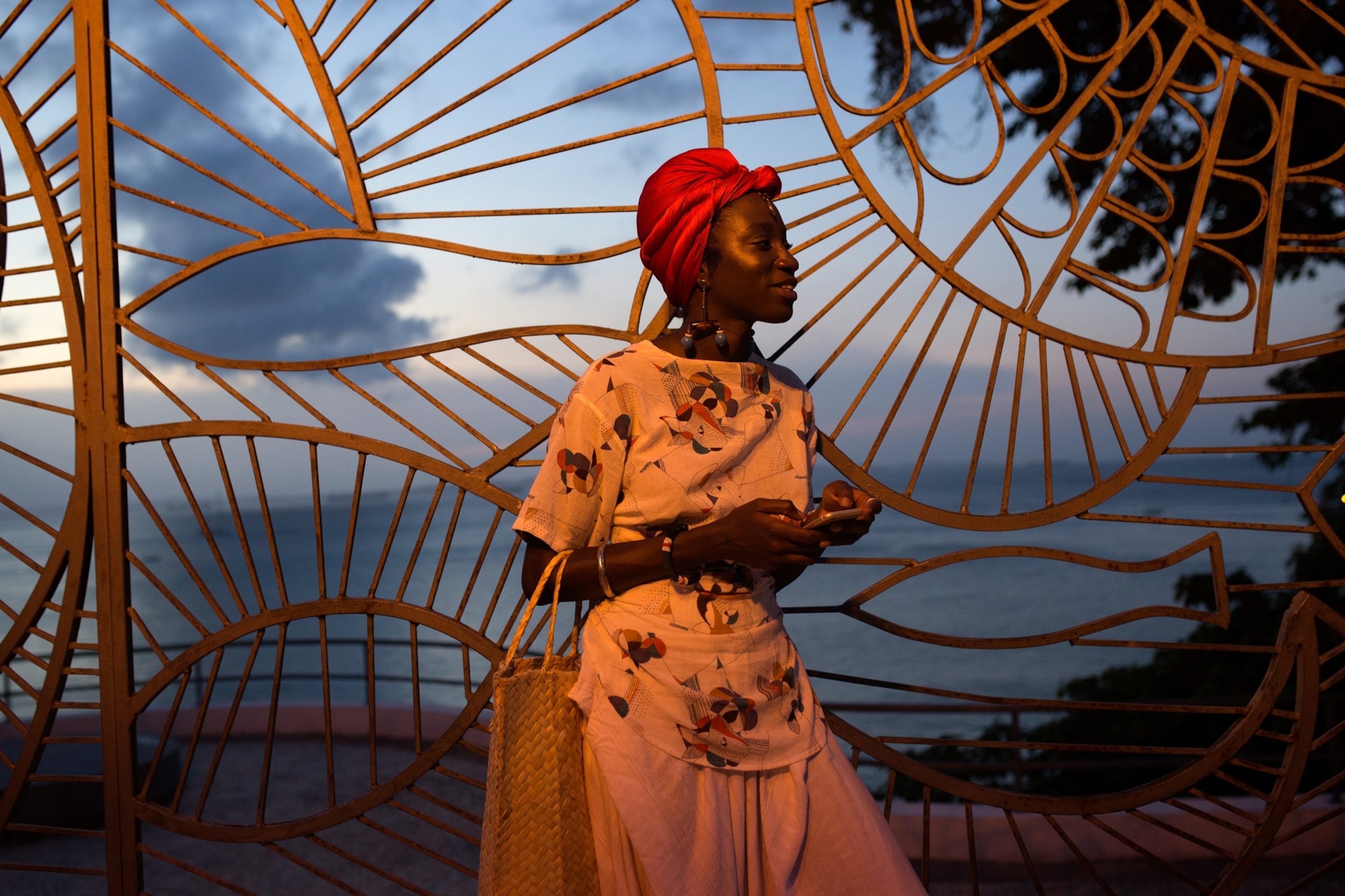 a woman in front of the ocean at sunset