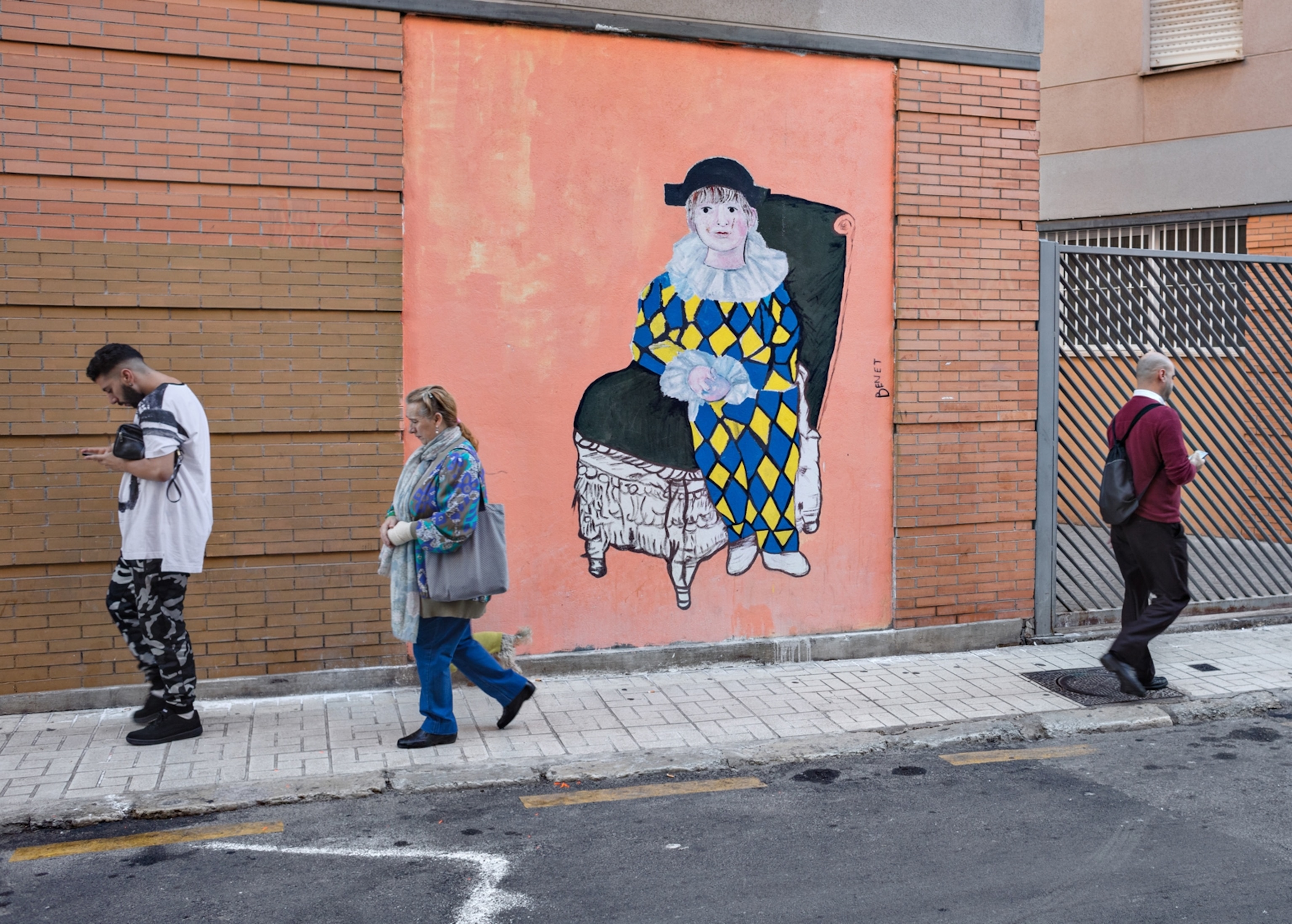 three people walking by a graffiti work on a of a Picasso painting on a peach background