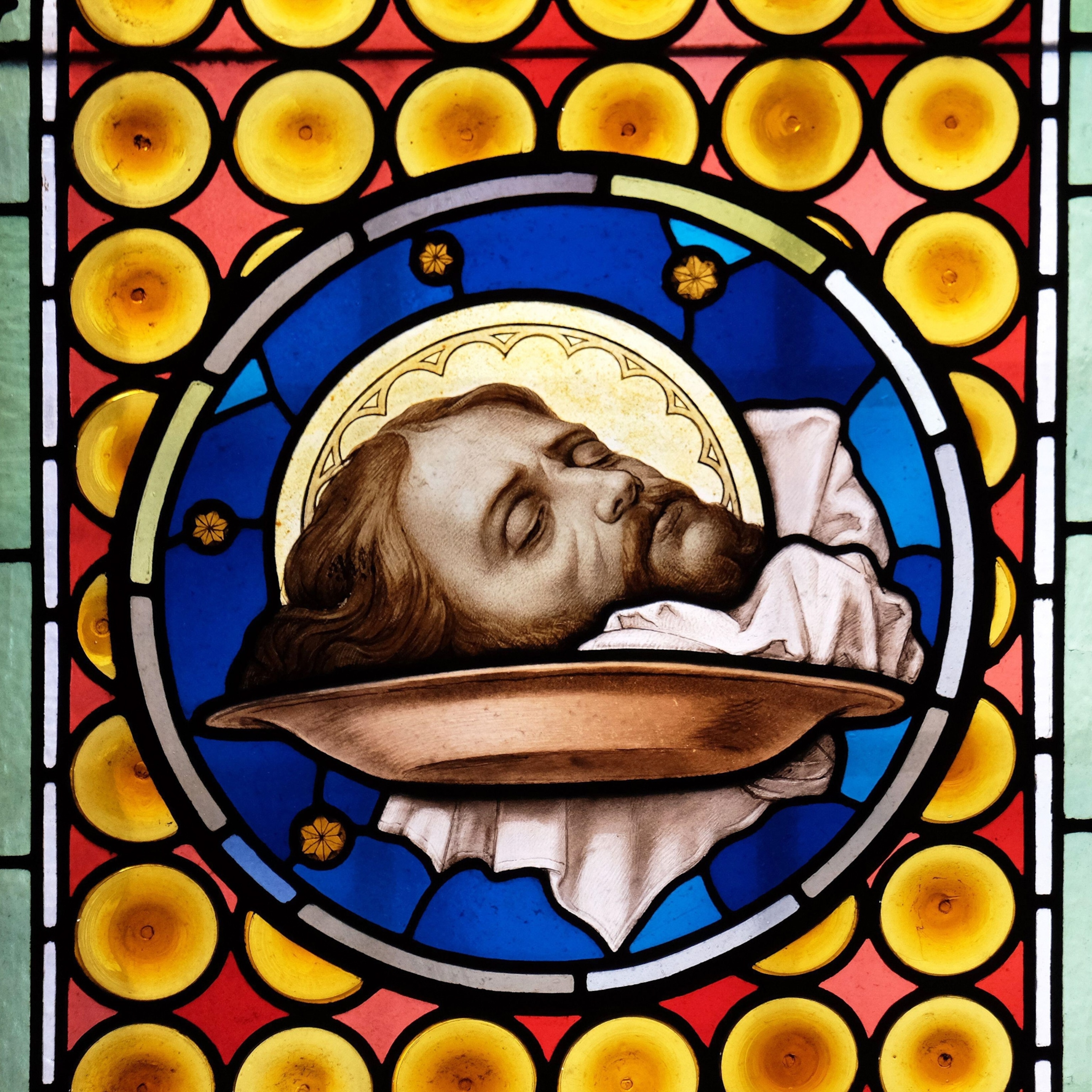 A stained glass depiction of the head of John the Baptist.