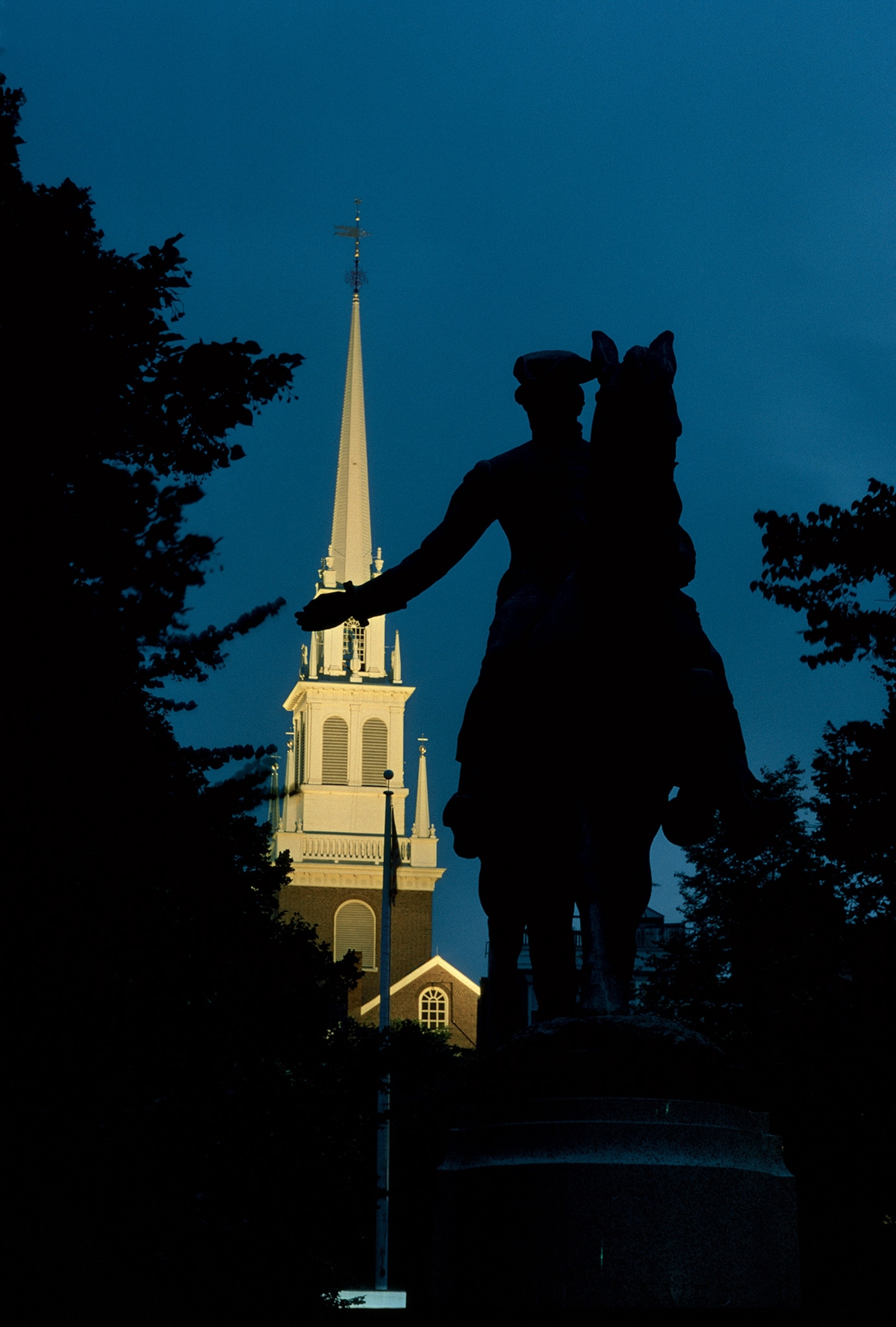 The silhouette of the Paul Revere sculpture sits in front of Boston’s Old North Church.