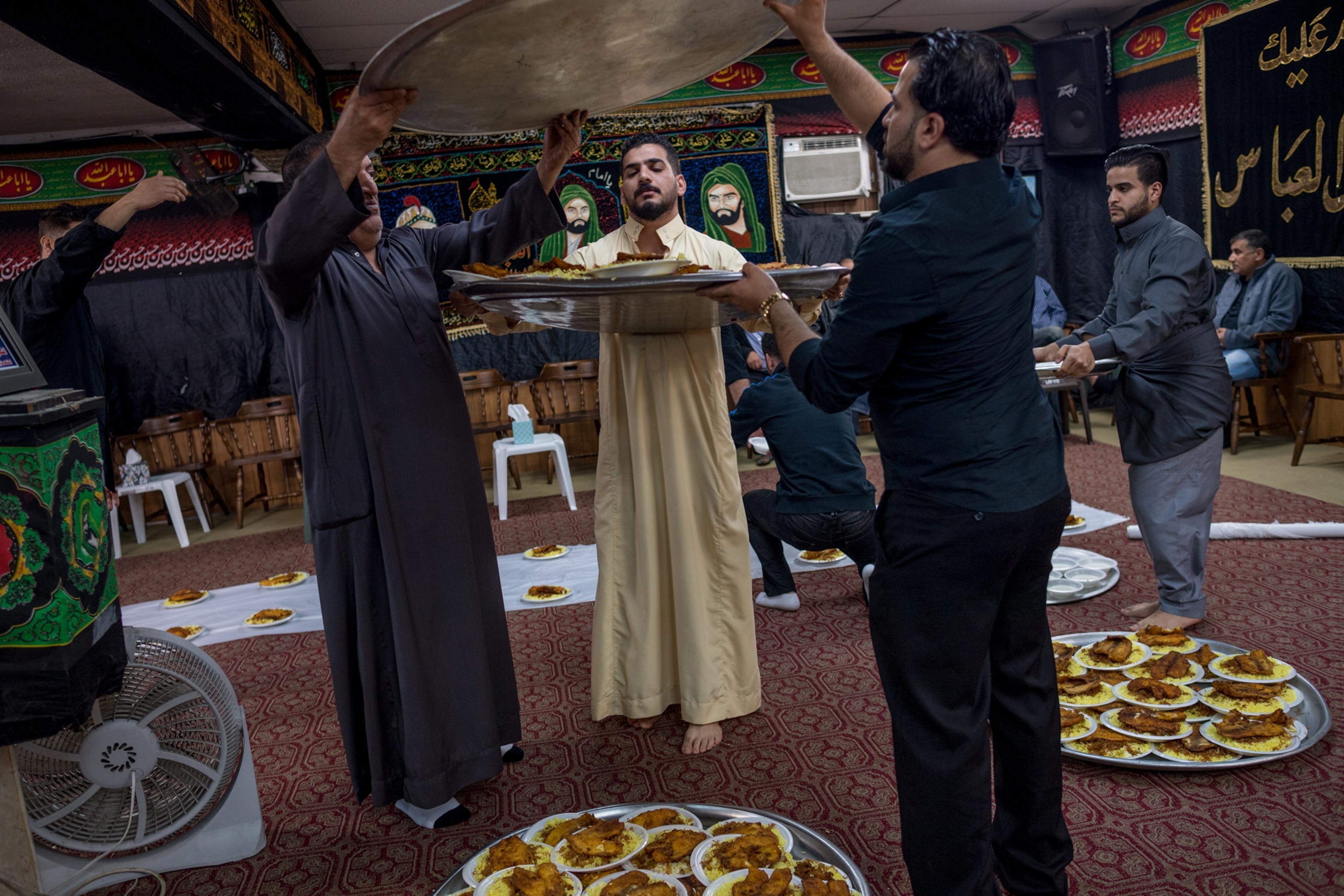 men holding platters with fish during a traditional Iraqi funeral