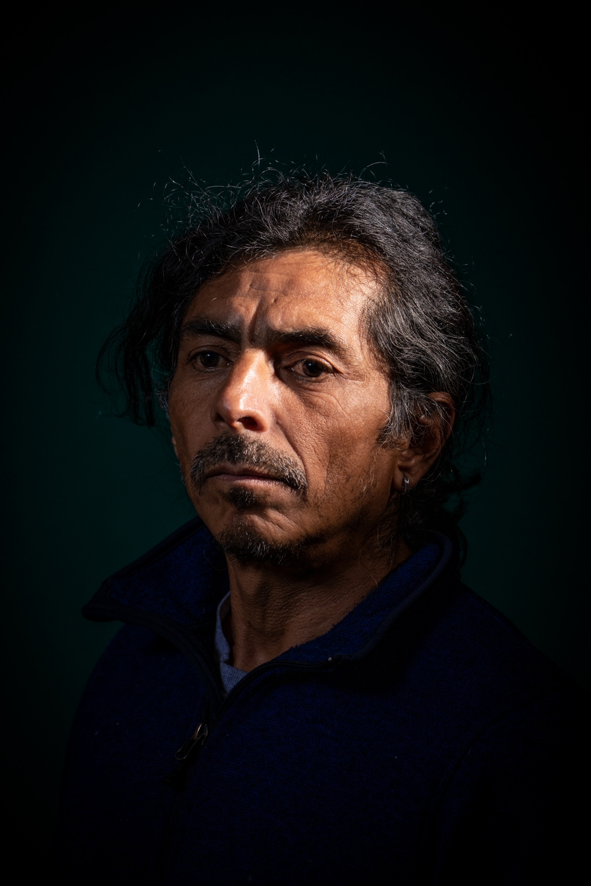 a dimly lit man standing for a portrait