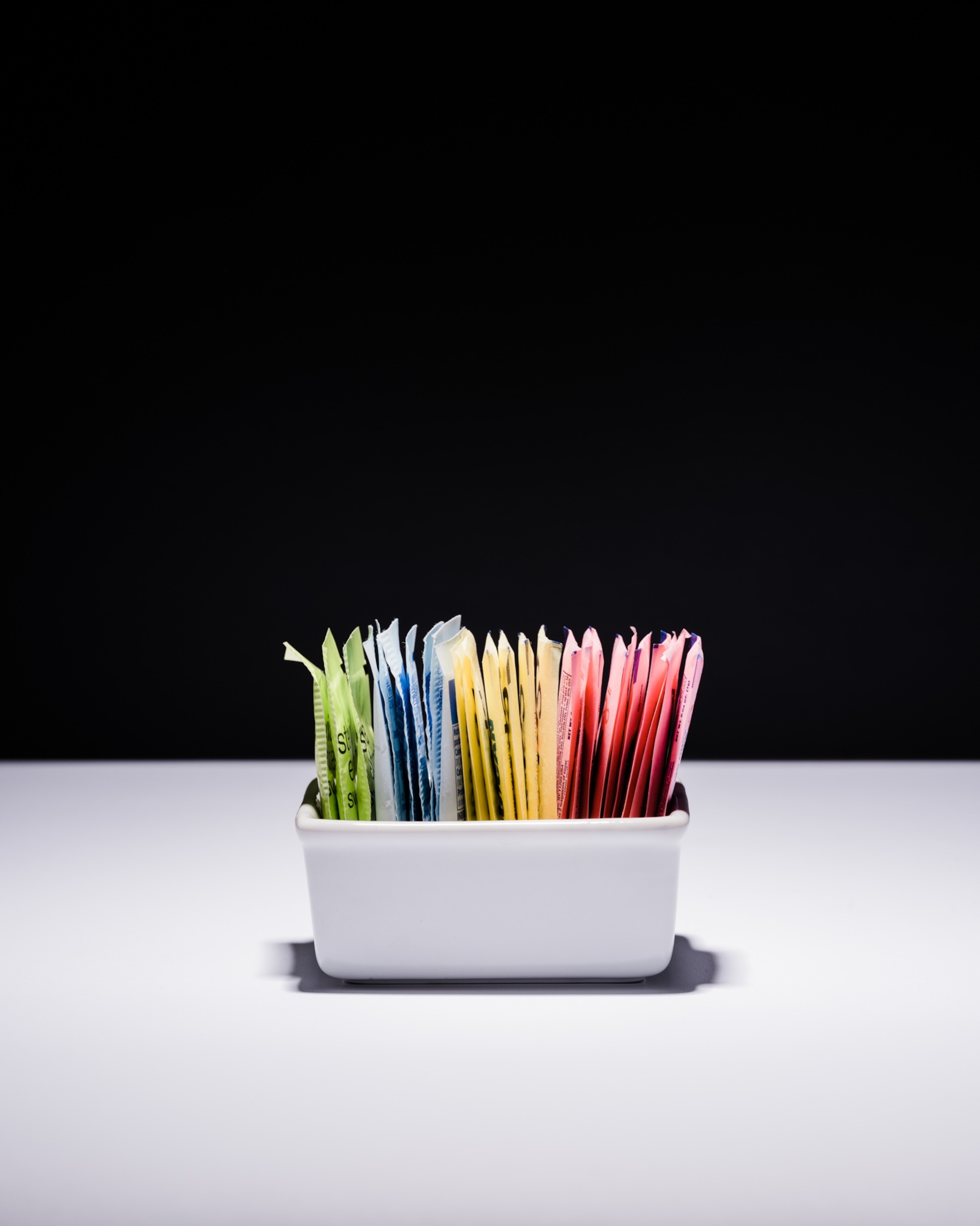 Studio shoot with black backdrop showing packets of artificial sweeteners