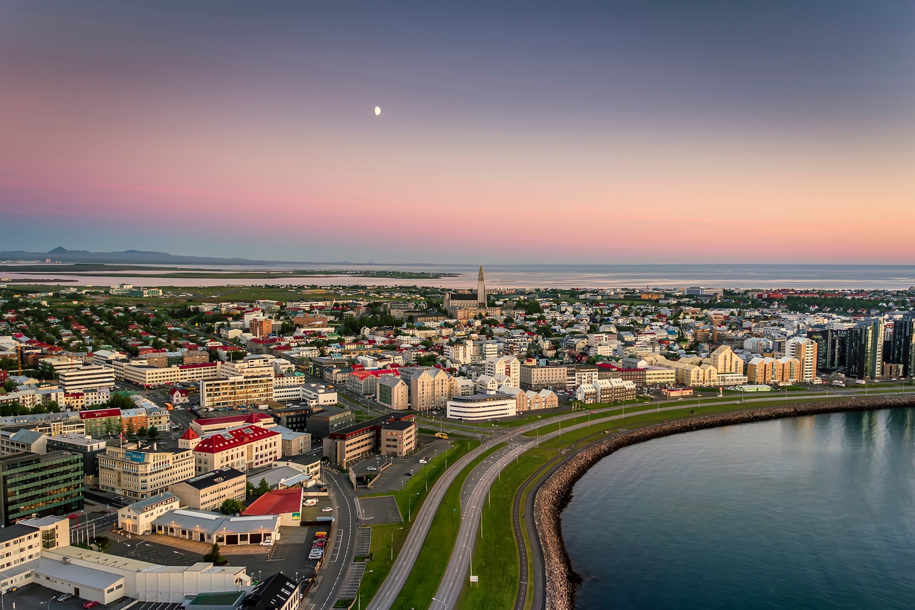 A birdeye view of a lakeside town where the sky is dusky and the moon has risen