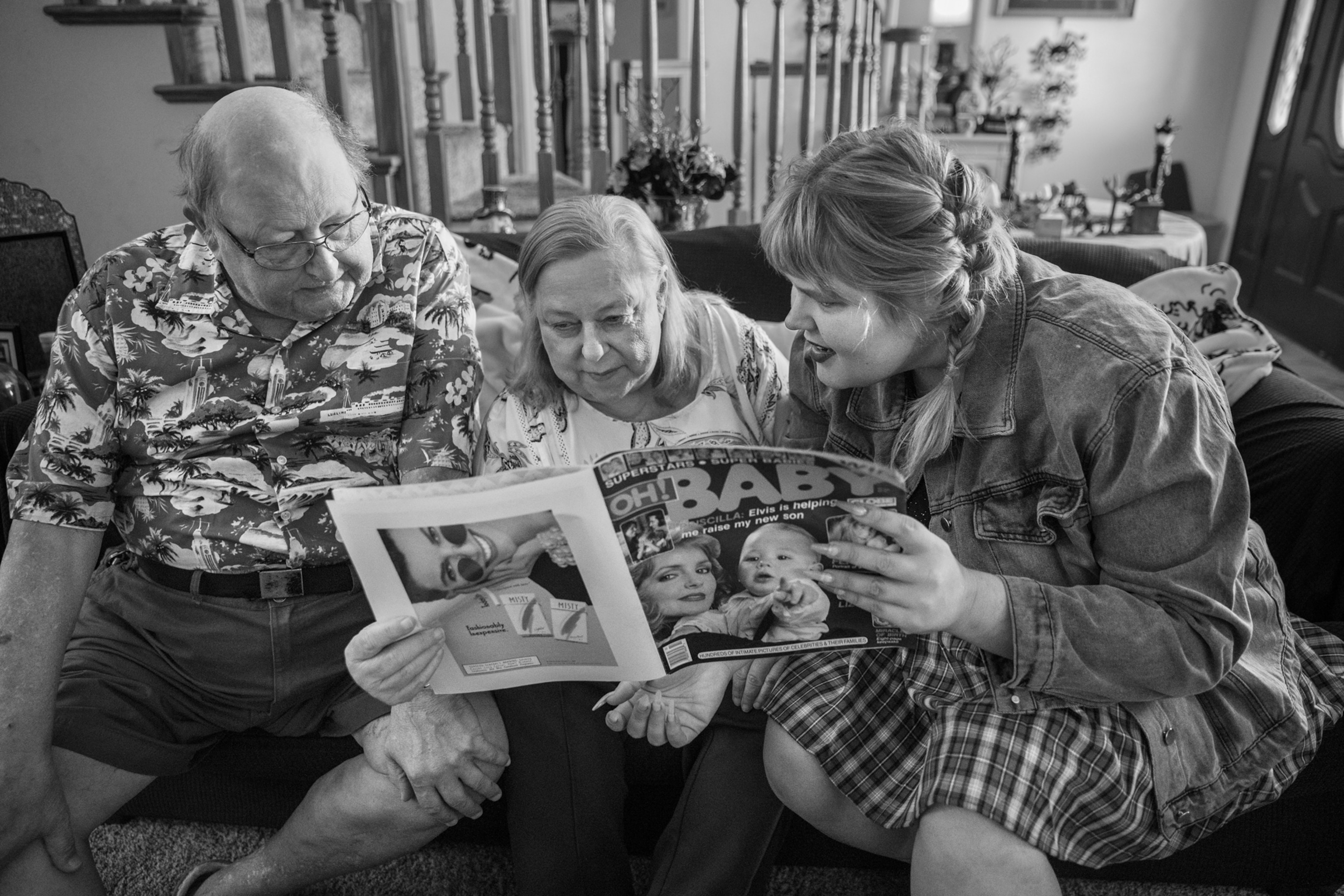 Older man and woman on the couch with young woman reading old magazine with word "baby" on the cover.