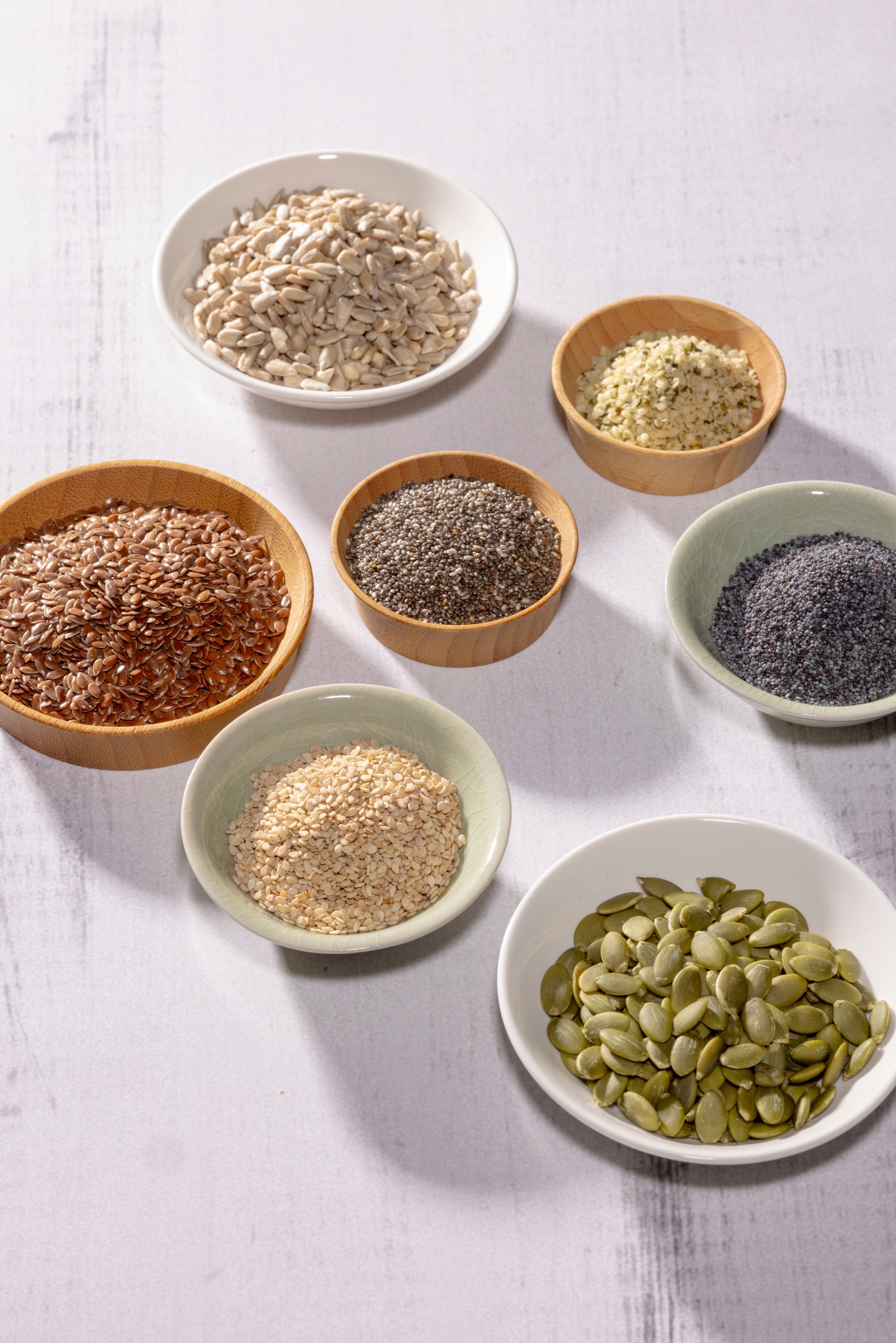 Image of seeds in bowls. Top row: sunflower and hemp seeds. Middle row: Flax, chia, and poppy, seeds. Bottom row: sesame and pumpkin seeds.