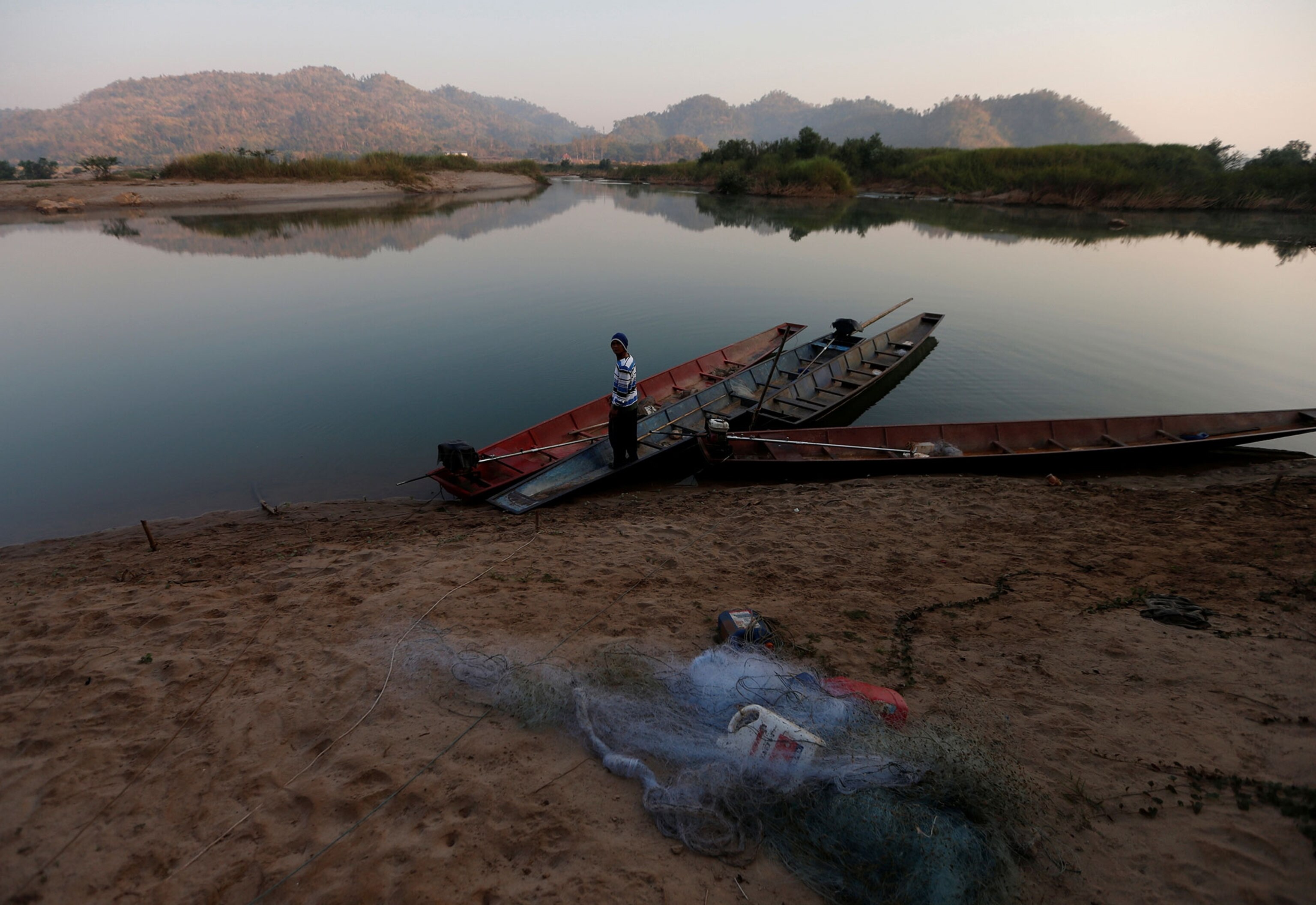 a fisherman on the banks of the Mekong river, which has turned an unhealthy blue