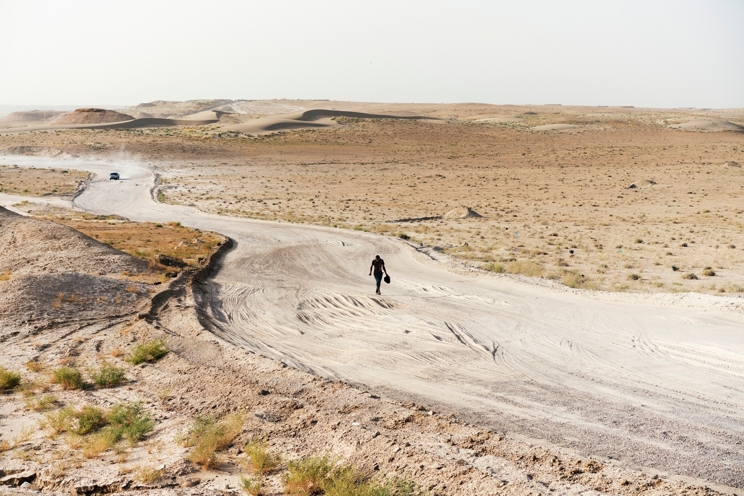 a man walking along a desert road