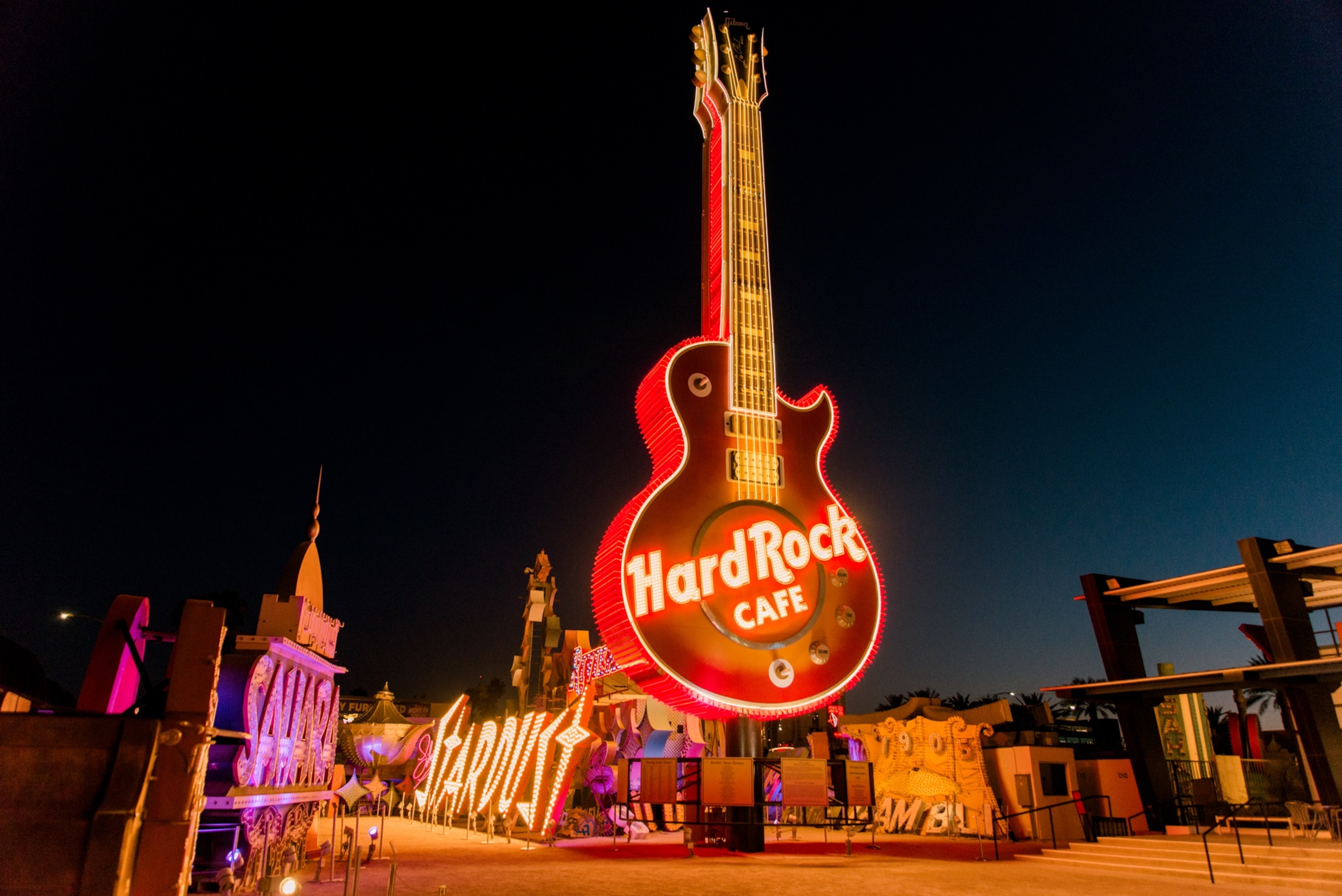 Giant Hard Rock and Stardust neon signs shine at night at The Neon Museum bone yard grounds