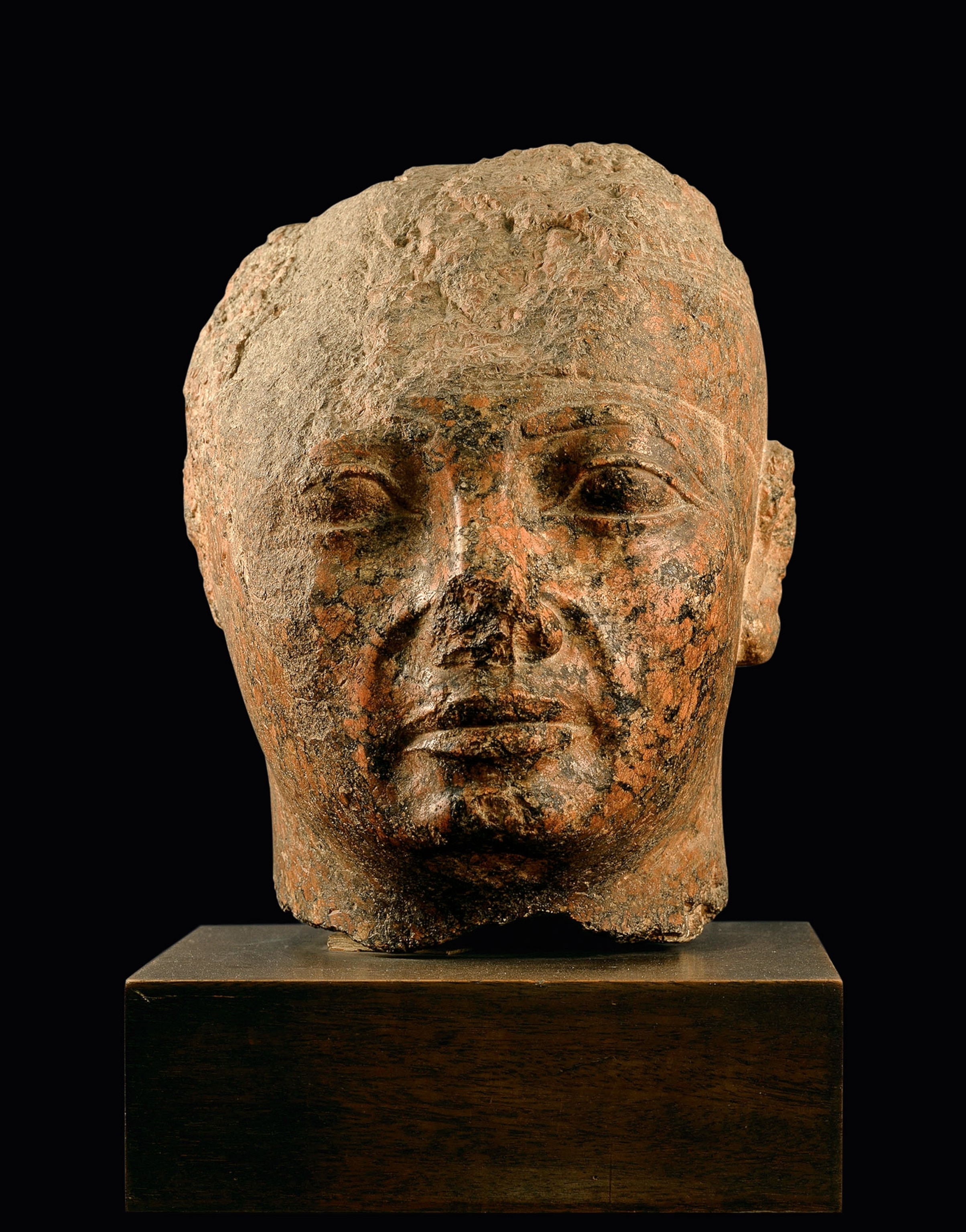 An age-worn statue of a head on a pedestal
