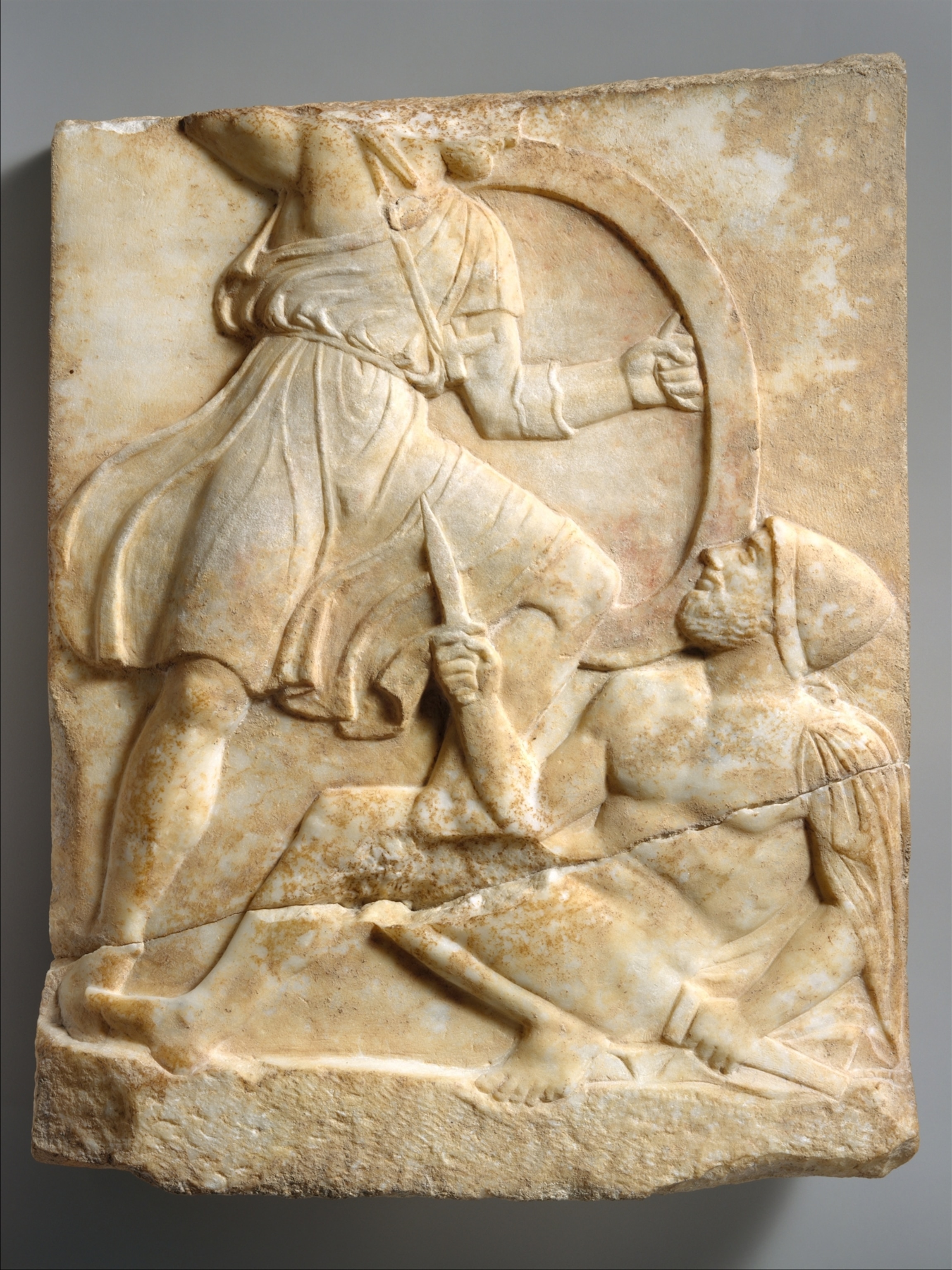A tablet shows a scene of battle a small blade in the hand of the person in the foreground the broken table obscures some of the detail.