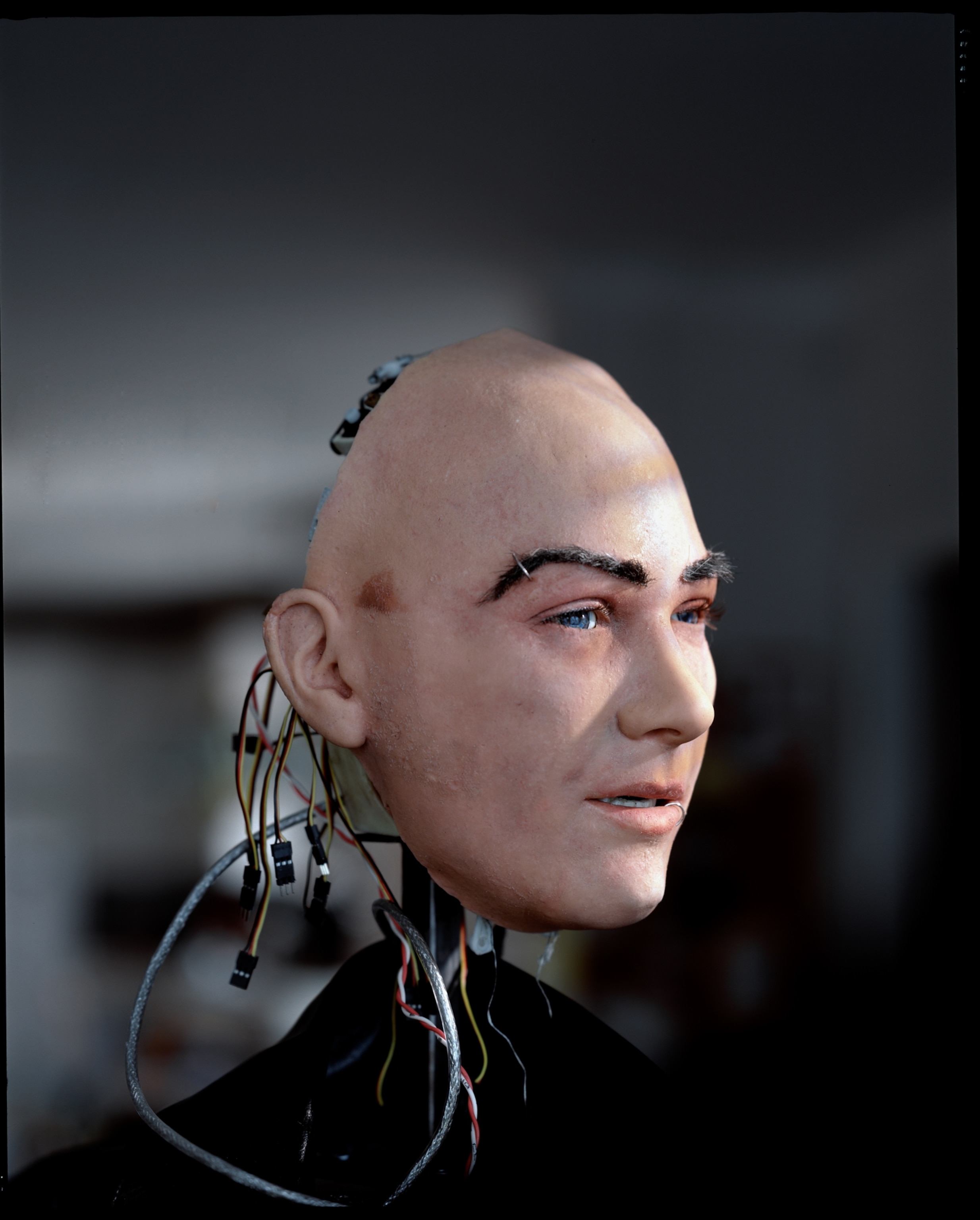 The head of a partially assembled robot; its face appearing eerily life-like.