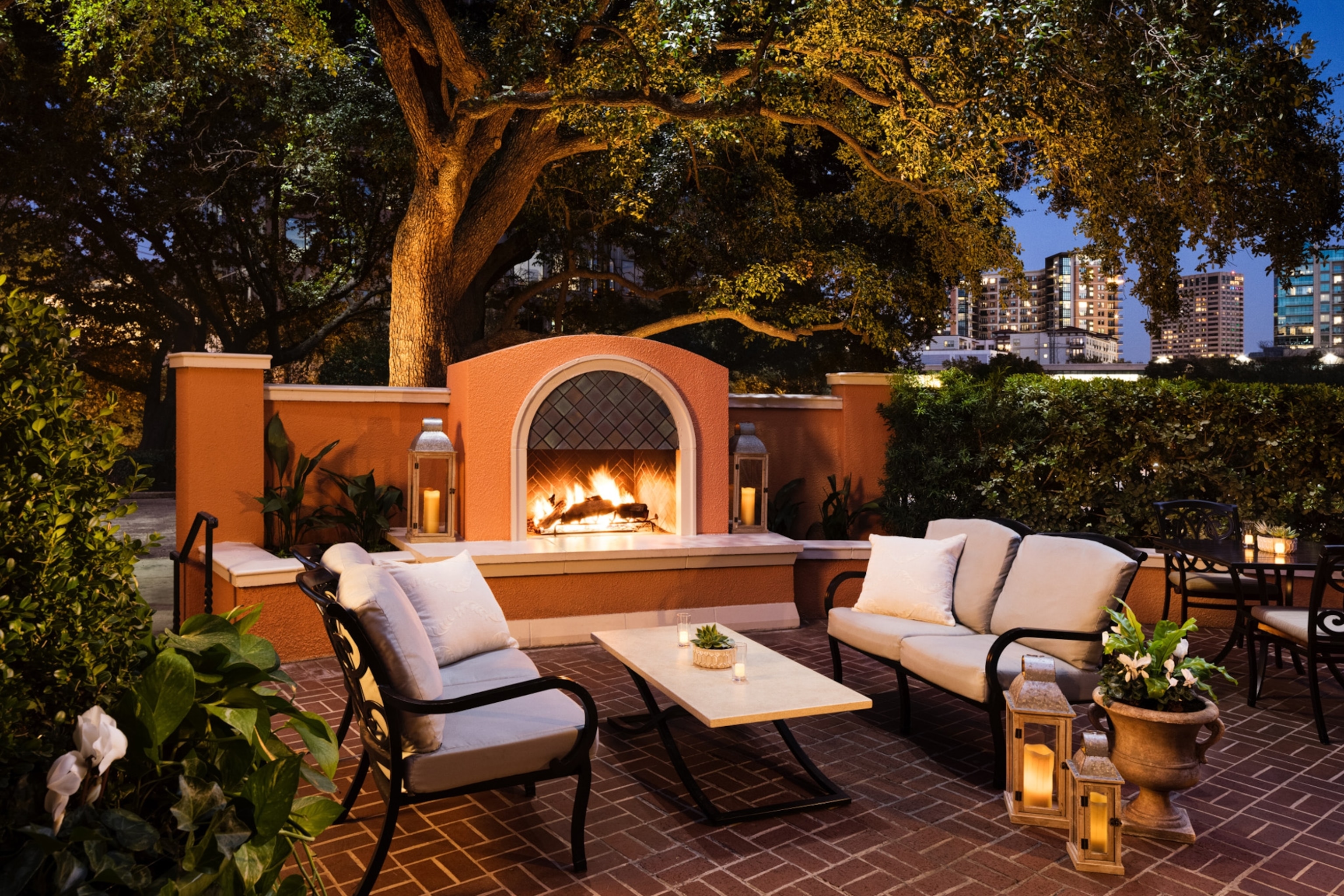 An outdoor fire pit area with table and chairs in front of it.